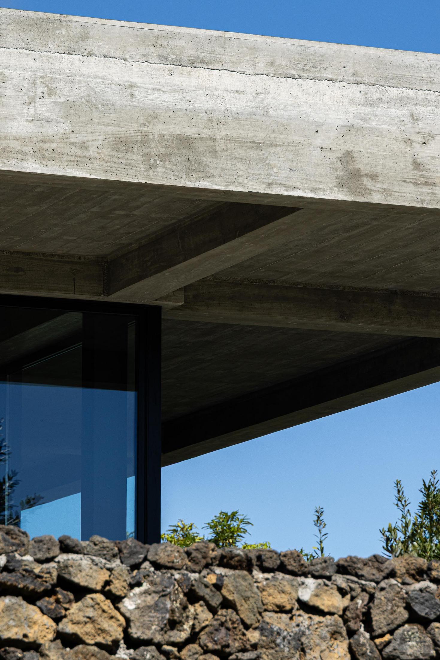 Exterior: Teto em betão aparente e muro de pedra vulcânica. — Casa CR arquitetura SO Arquitetura & Design em São Miguel