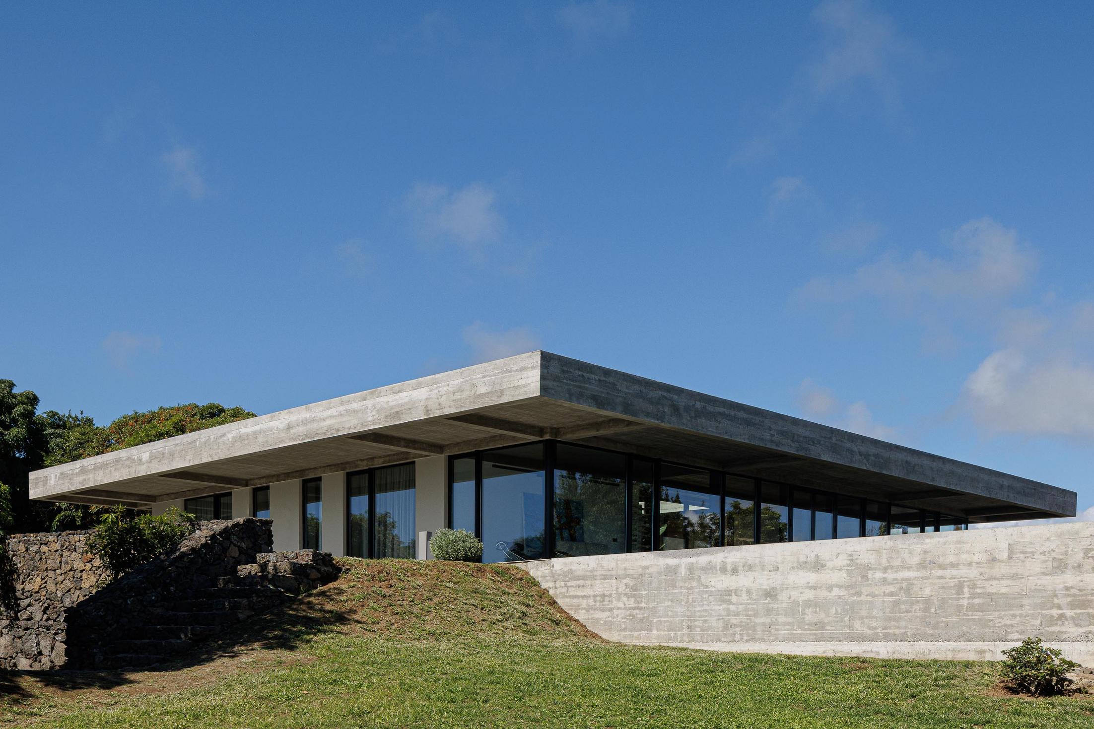 Exterior: Vista geral da casa com teto em betão aparente e relvado. — Casa CR arquitetura SO Arquitetura & Design em São Miguel