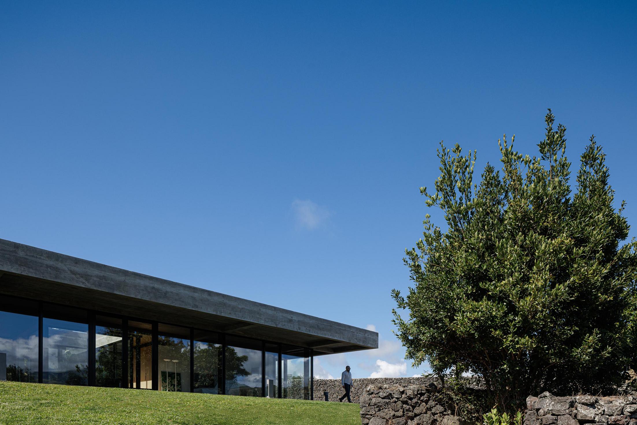 Exterior: Fachada da casa com teto em betão aparente e relvado. — Casa CR arquitetura SO Arquitetura & Design em São Miguel