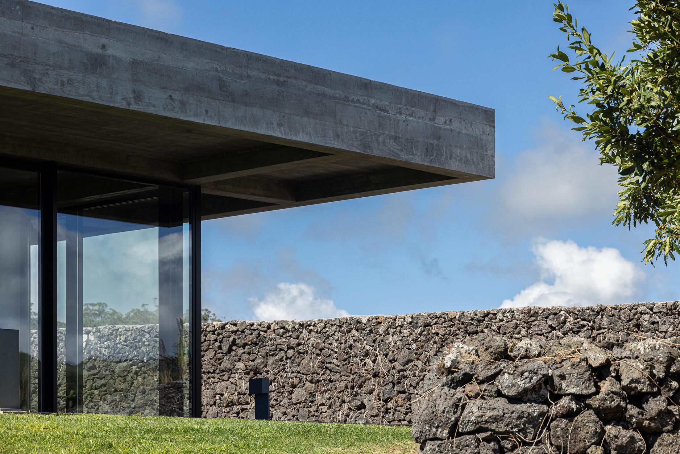 Exterior: Teto em betão aparente e muro de pedra vulcânica. — Casa CR arquitetura SO Arquitetura & Design em São Miguel