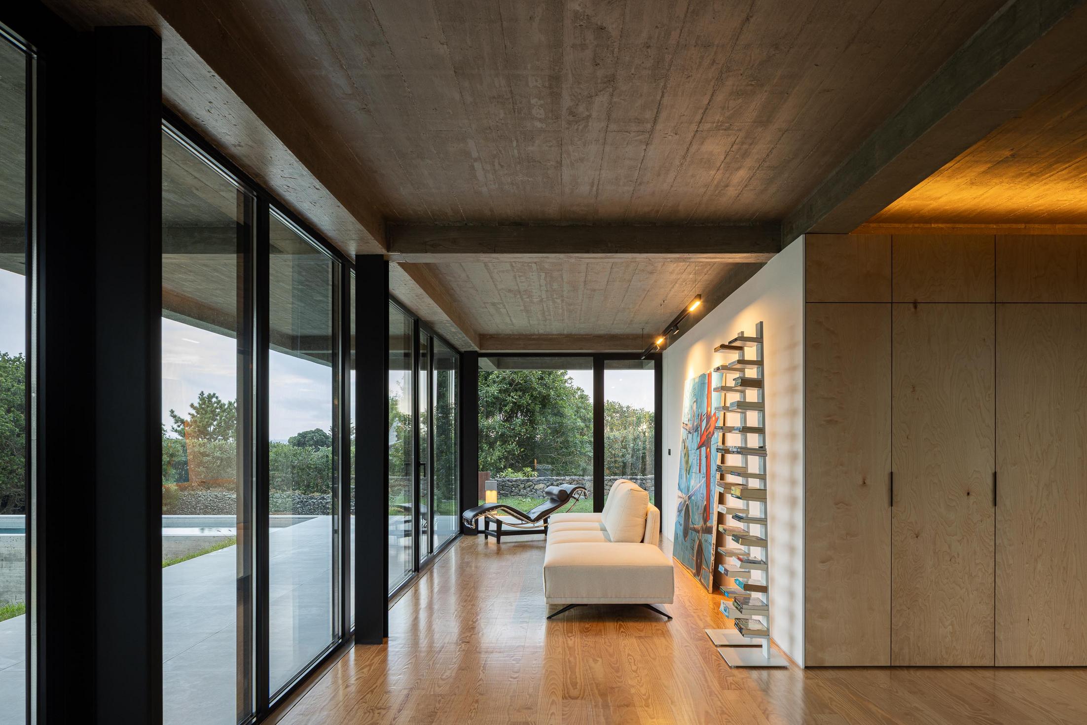 Sala de estar: Grandes janelas, sofá branco e estante com livros. — Casa CR arquitetura SO Arquitetura & Design em São Miguel