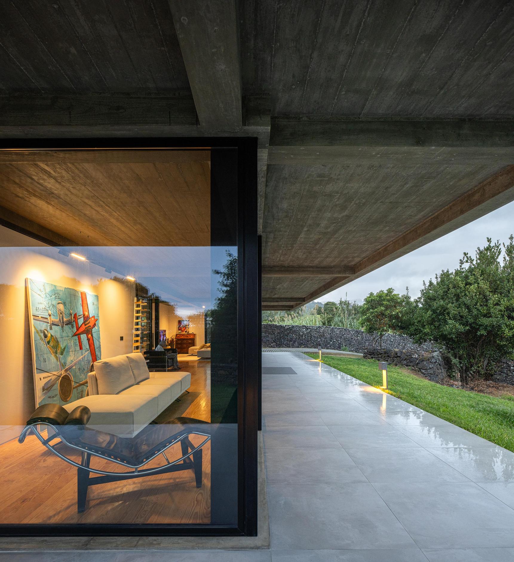 Exterior: Fachada da casa com teto em betão aparente e relvado. — Casa CR arquitetura SO Arquitetura & Design em São Miguel