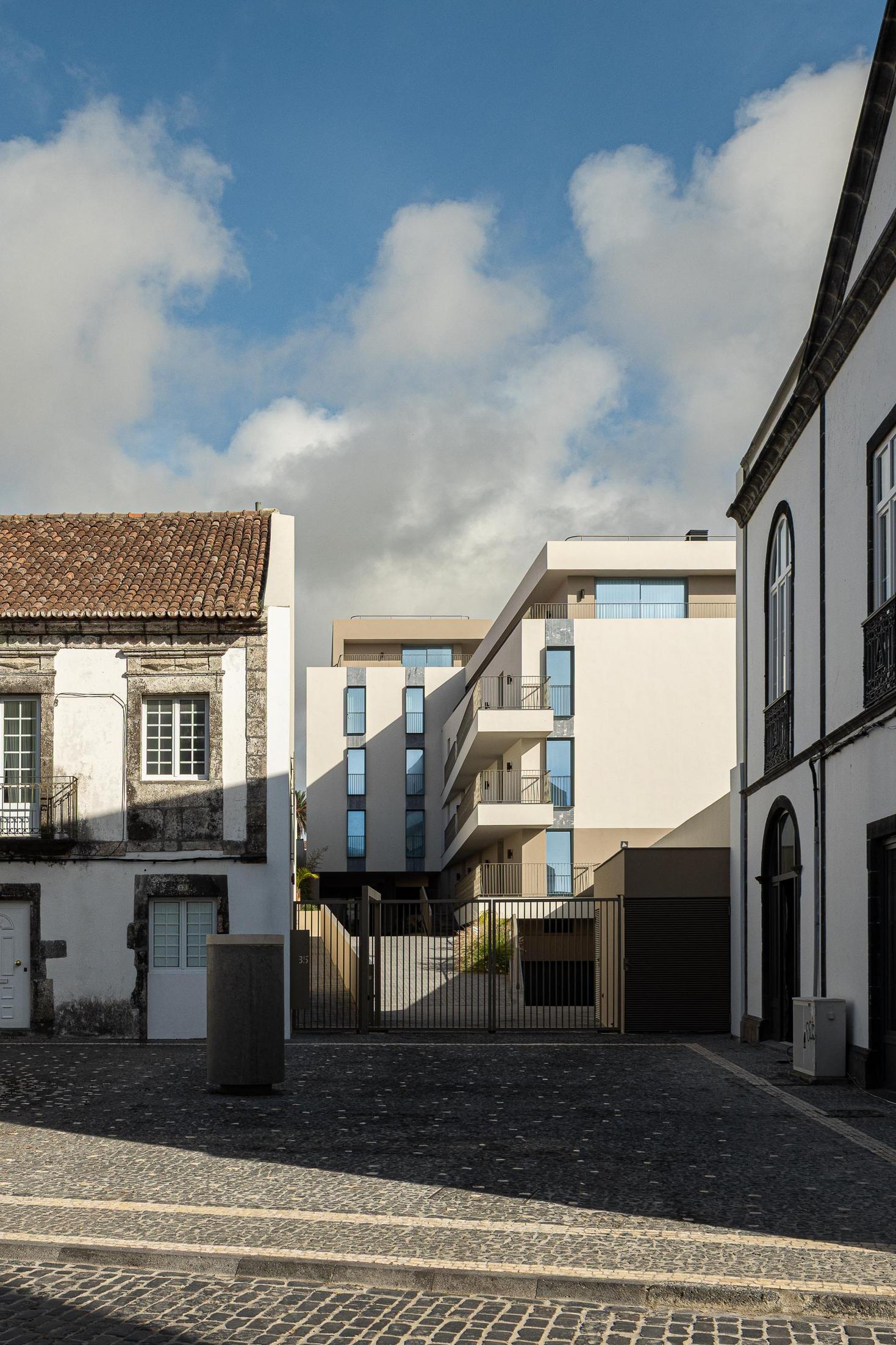 Rua: Edifício moderno integrado na malha urbana histórica, com ruas em calçada. — ERNESTO DO CANTO - condomínio arquitetura BOX arquitectos em Ponta Delgada
