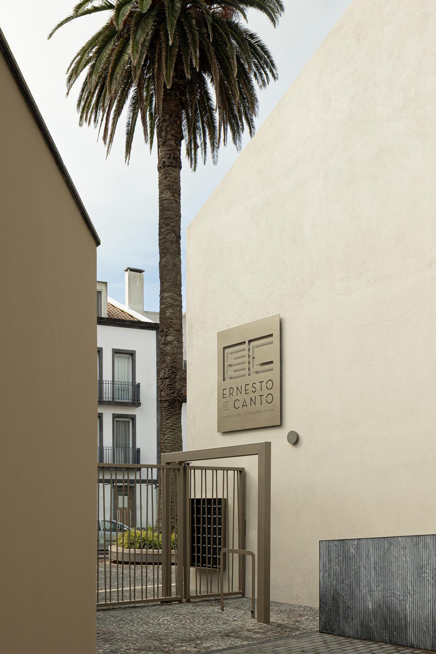 Entrada: Placa com o nome do condomínio "Ernesto do Canto" e portão de acesso. — ERNESTO DO CANTO - condomínio arquitetura BOX arquitectos em Ponta Delgada