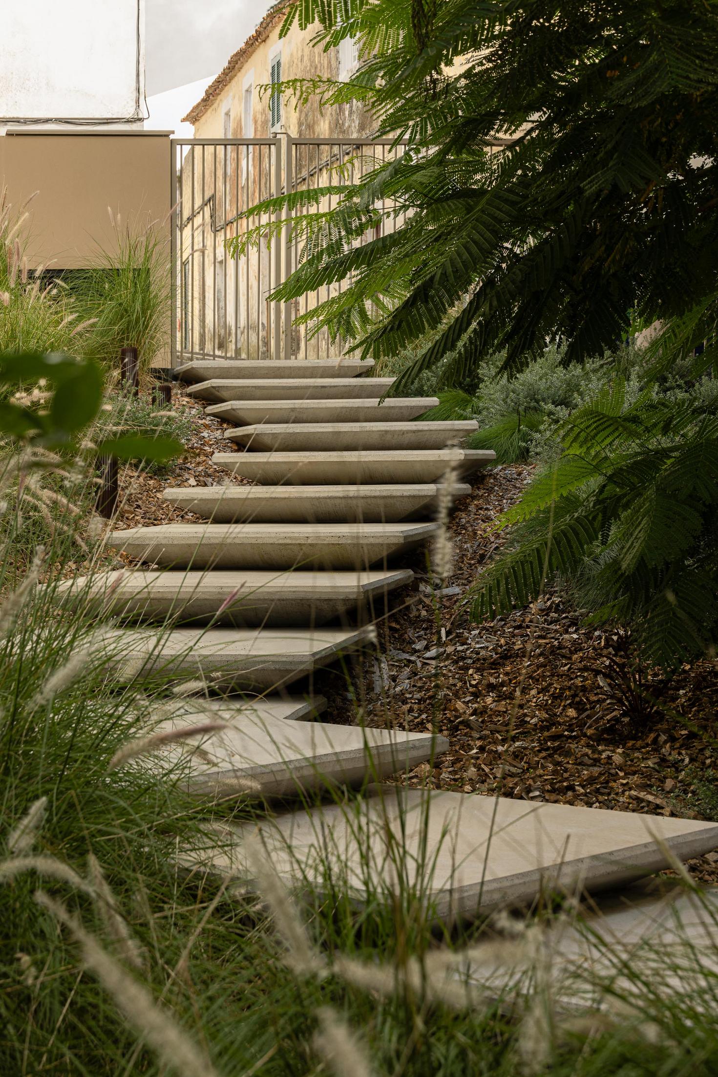 Jardim: Escadas de acesso ao jardim, com vegetação e pavimento em calçada. — ERNESTO DO CANTO - condomínio arquitetura BOX arquitectos em Ponta Delgada