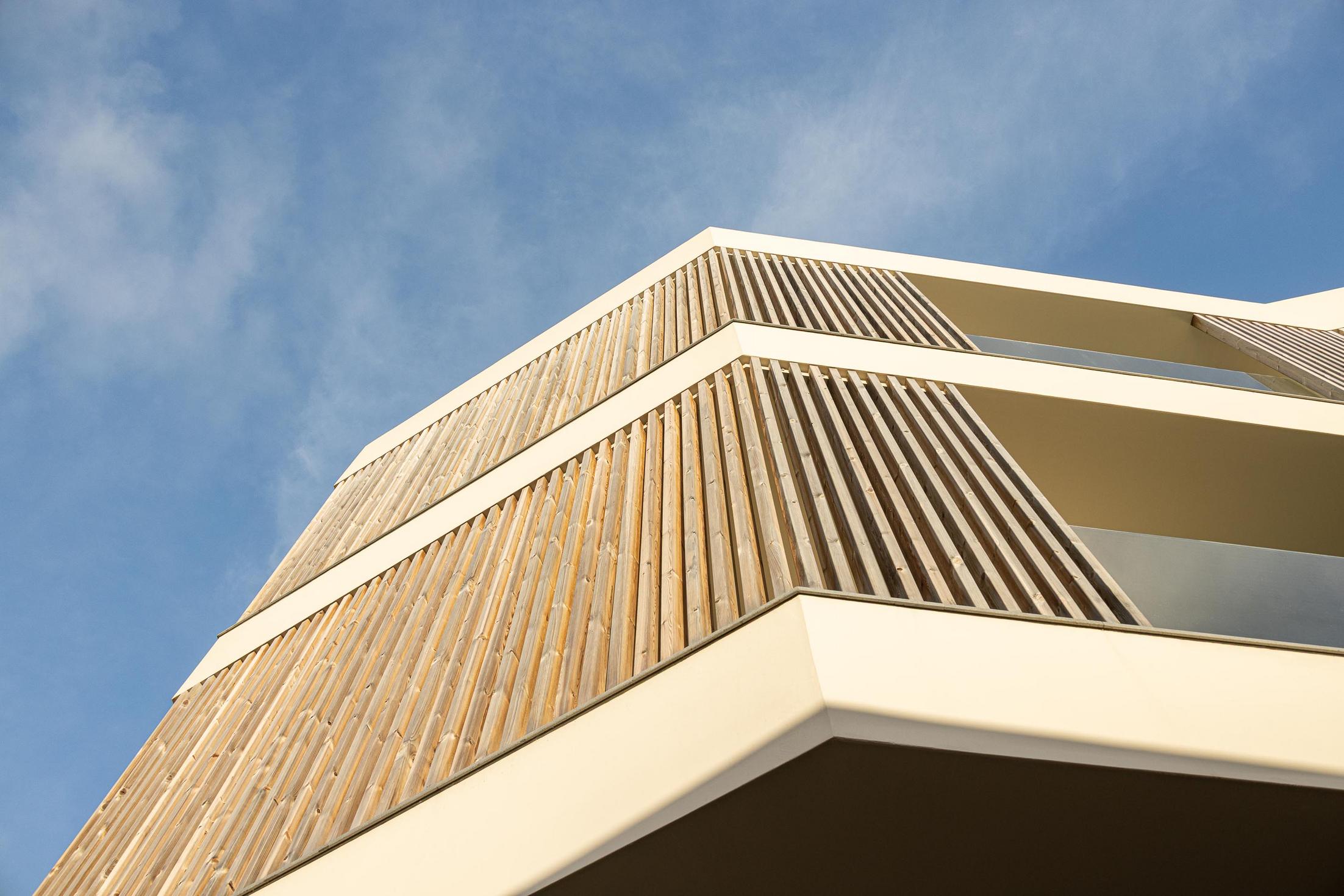 Fachada: Detalhe das varandas com ripas de madeira e vidro. — ERNESTO DO CANTO - condomínio arquitetura BOX arquitectos em Ponta Delgada