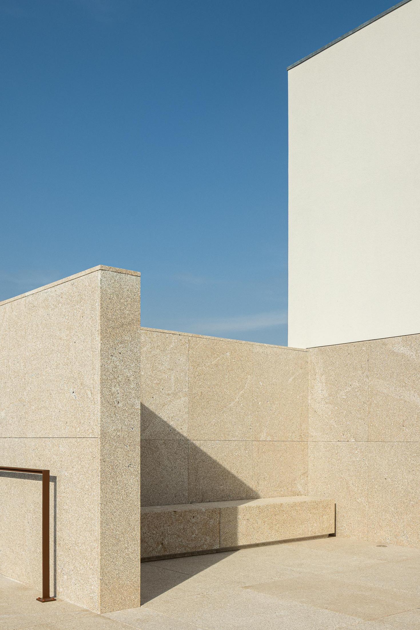 Exterior: Detalhe do pátio com paredes e banco em granito, e corrimão metálico. — Casa Mortuária São Martinho do Campo arquitetura Multiprojectus em Santo Tirso