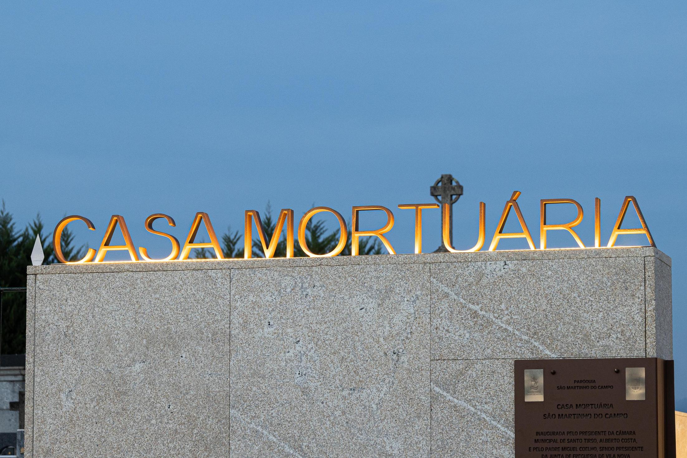Exterior: Placa iluminada com o nome "Casa Mortuária" e informações sobre a inauguração. — Casa Mortuária São Martinho do Campo arquitetura Multiprojectus em Santo Tirso