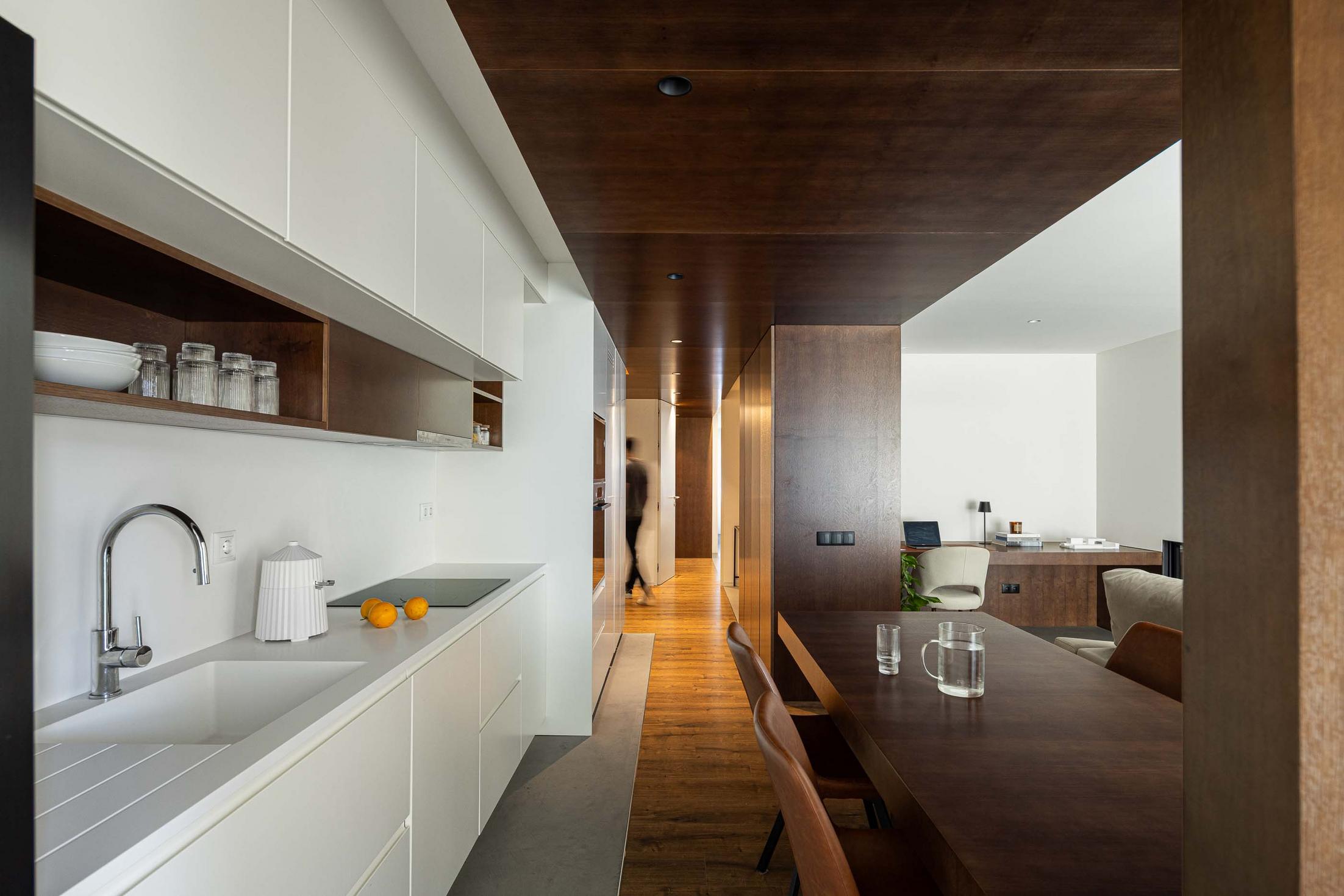 Cozinha/Escritório: Lavatório branco. Pavimento em madeira e cimento. Escritório ao fundo com secretária em madeira. — APARTAMENTO FP arquitetura ArquitectosRT em Braga