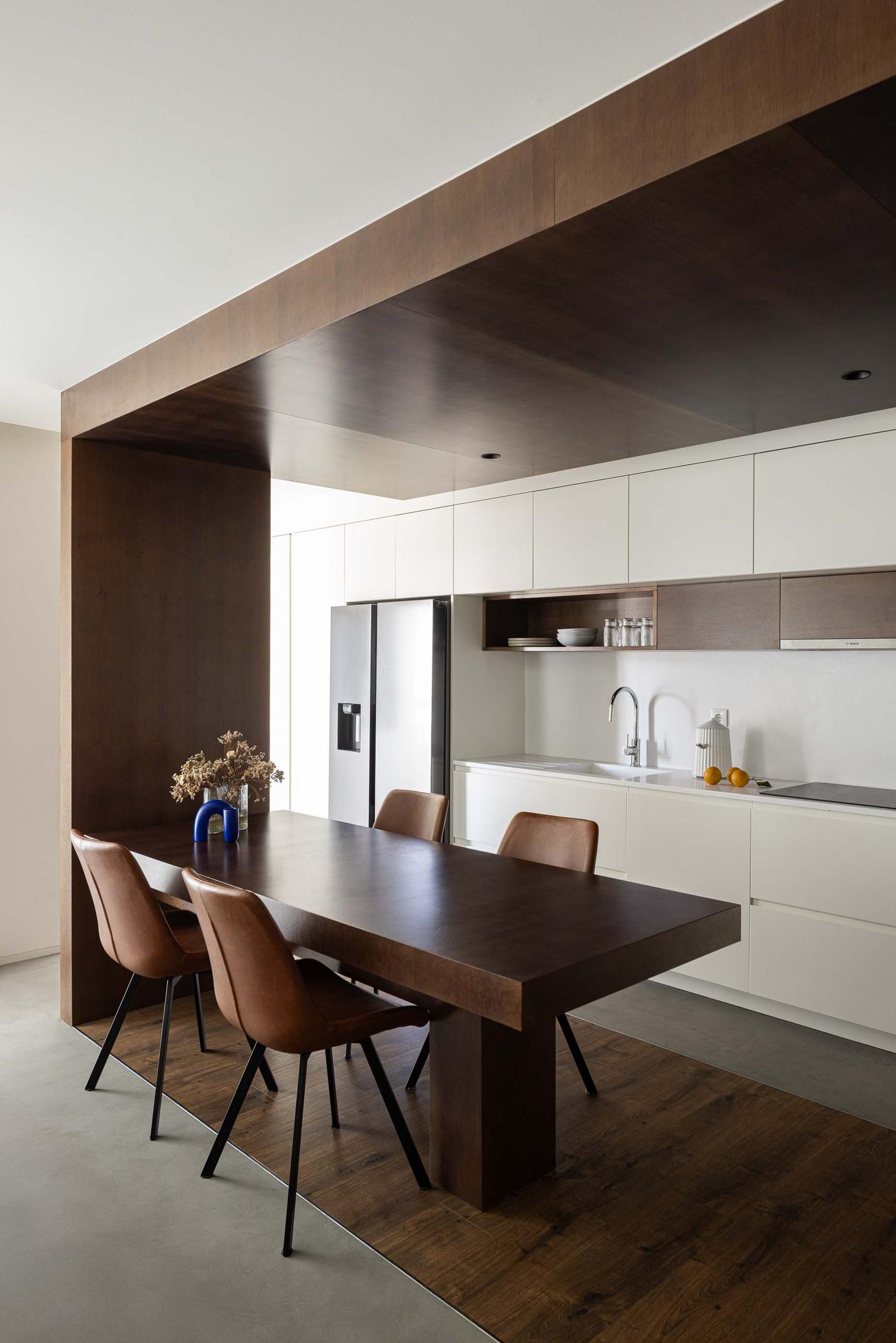 Cozinha/Sala de jantar: Mesa de madeira escura com cadeiras em pele castanha. Pavimento em madeira e cimento. — APARTAMENTO FP arquitetura ArquitectosRT em Braga