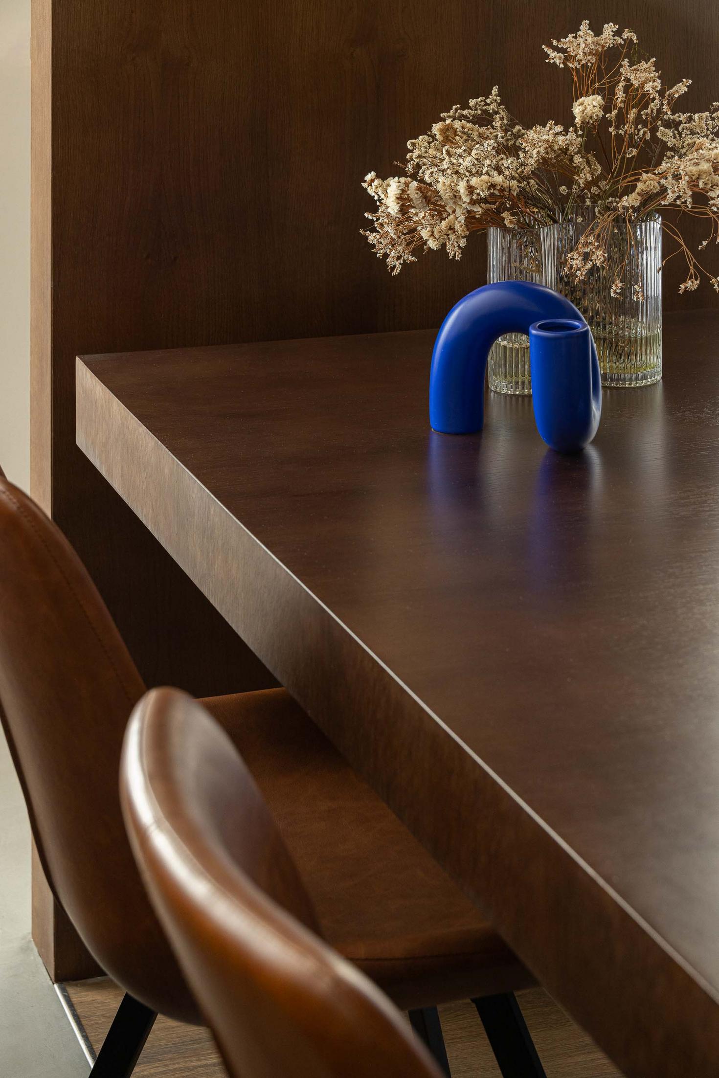 Sala de jantar: Detalhe da mesa de madeira escura com cadeiras em pele castanha e decoração moderna. — APARTAMENTO FP arquitetura ArquitectosRT em Braga