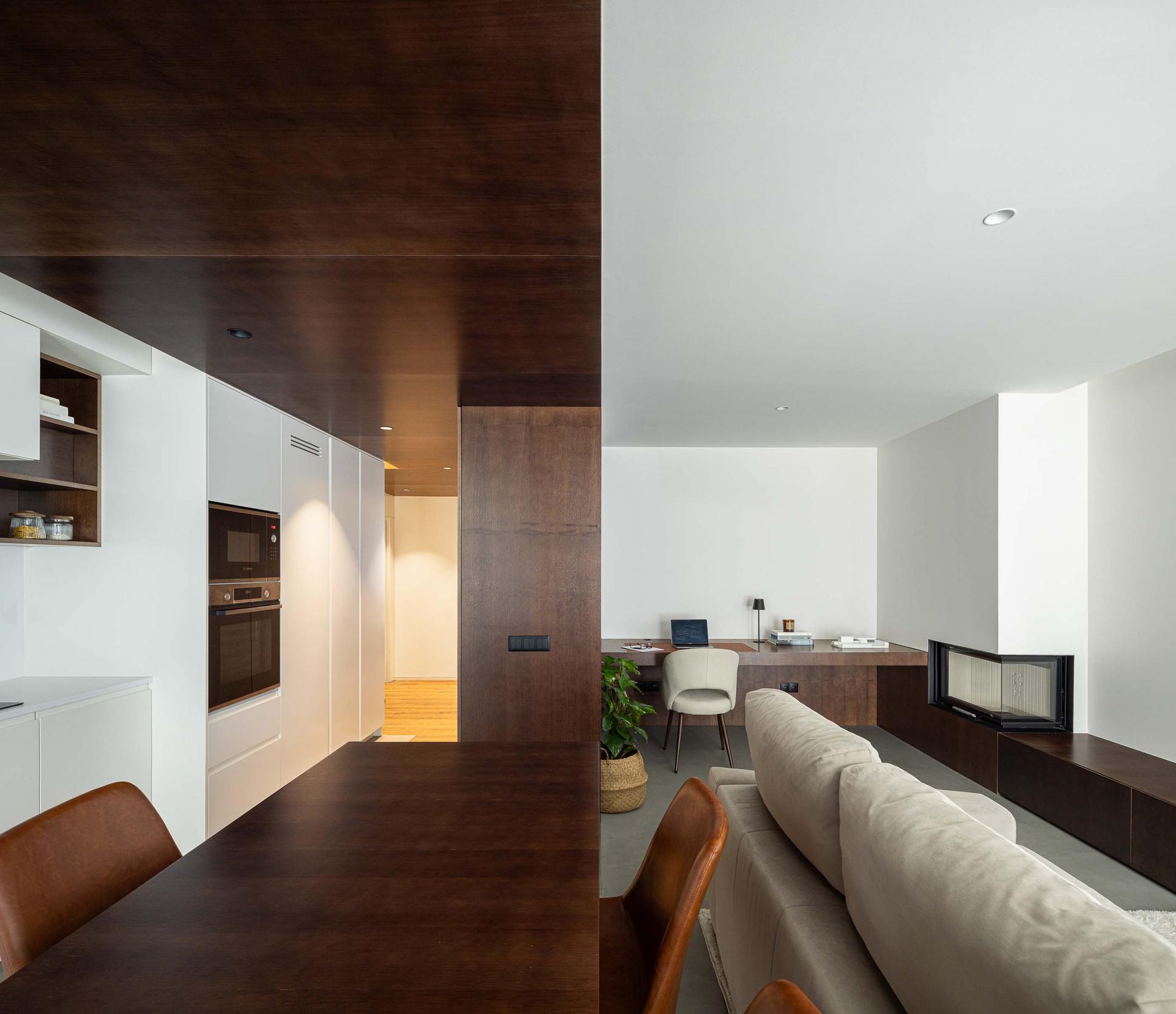 Sala de estar/Cozinha: Lareira moderna. Secretária em madeira. Mesa de madeira escura com cadeiras em pele castanha. — APARTAMENTO FP arquitetura ArquitectosRT em Braga