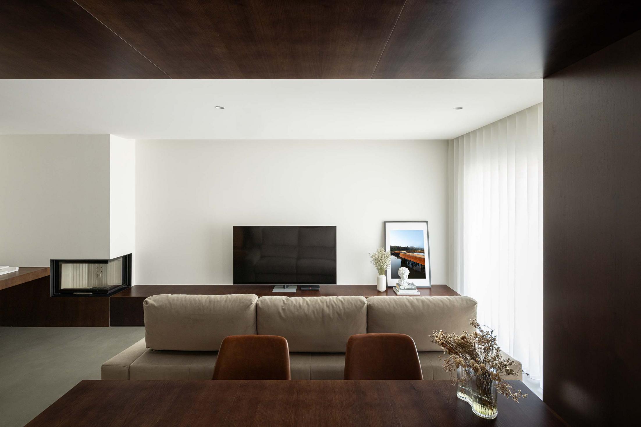 Sala de estar: Sofá branco. Móvel de televisão em madeira escura. Lareira moderna. Pavimento em cimento. — APARTAMENTO FP arquitetura ArquitectosRT em Braga