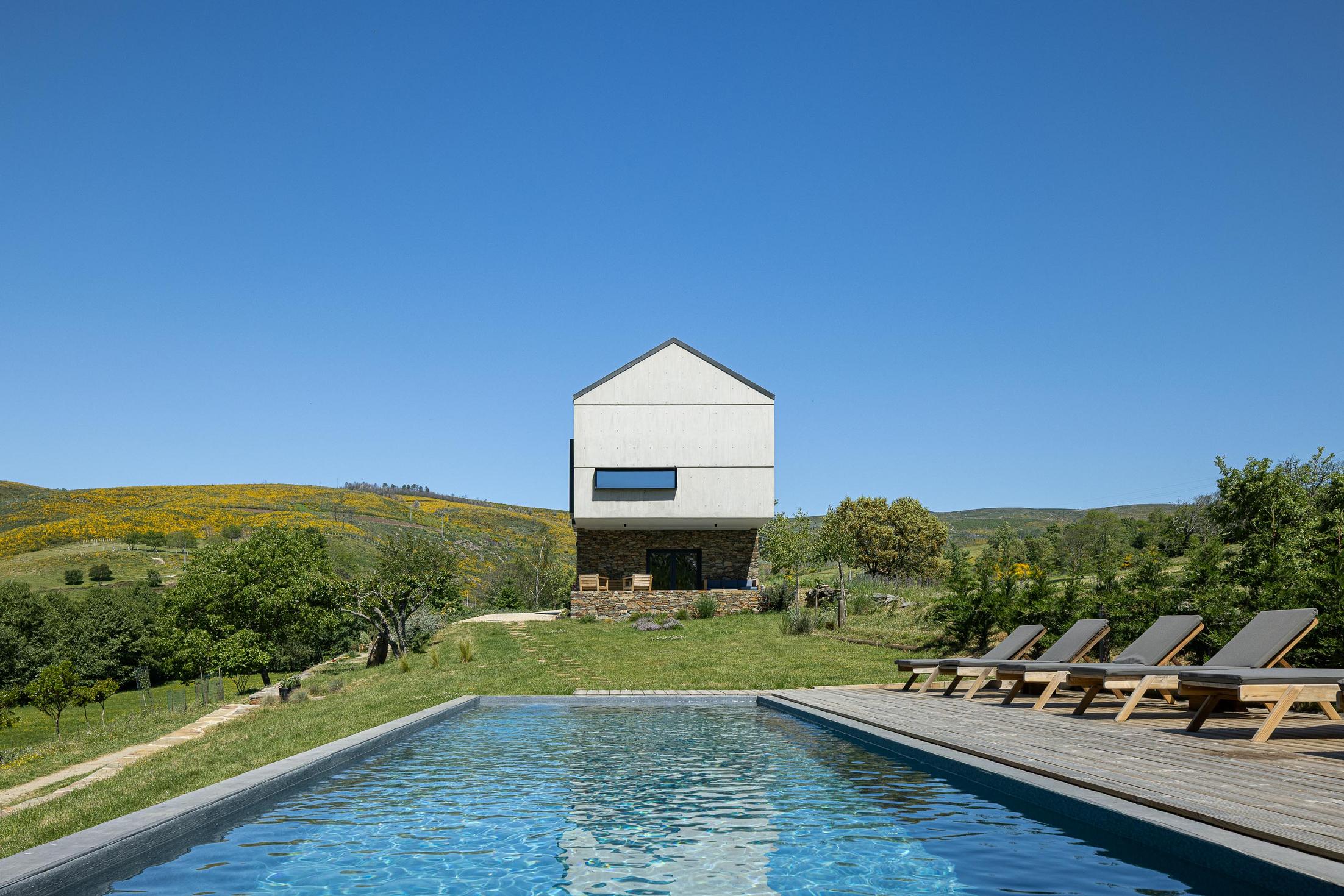 Exterior: Piscina com deck de madeira e casa com fachada em pedra e betão. — TerraSense Mountain Charm Retreat arquitetura DRK Atelier em Guarda