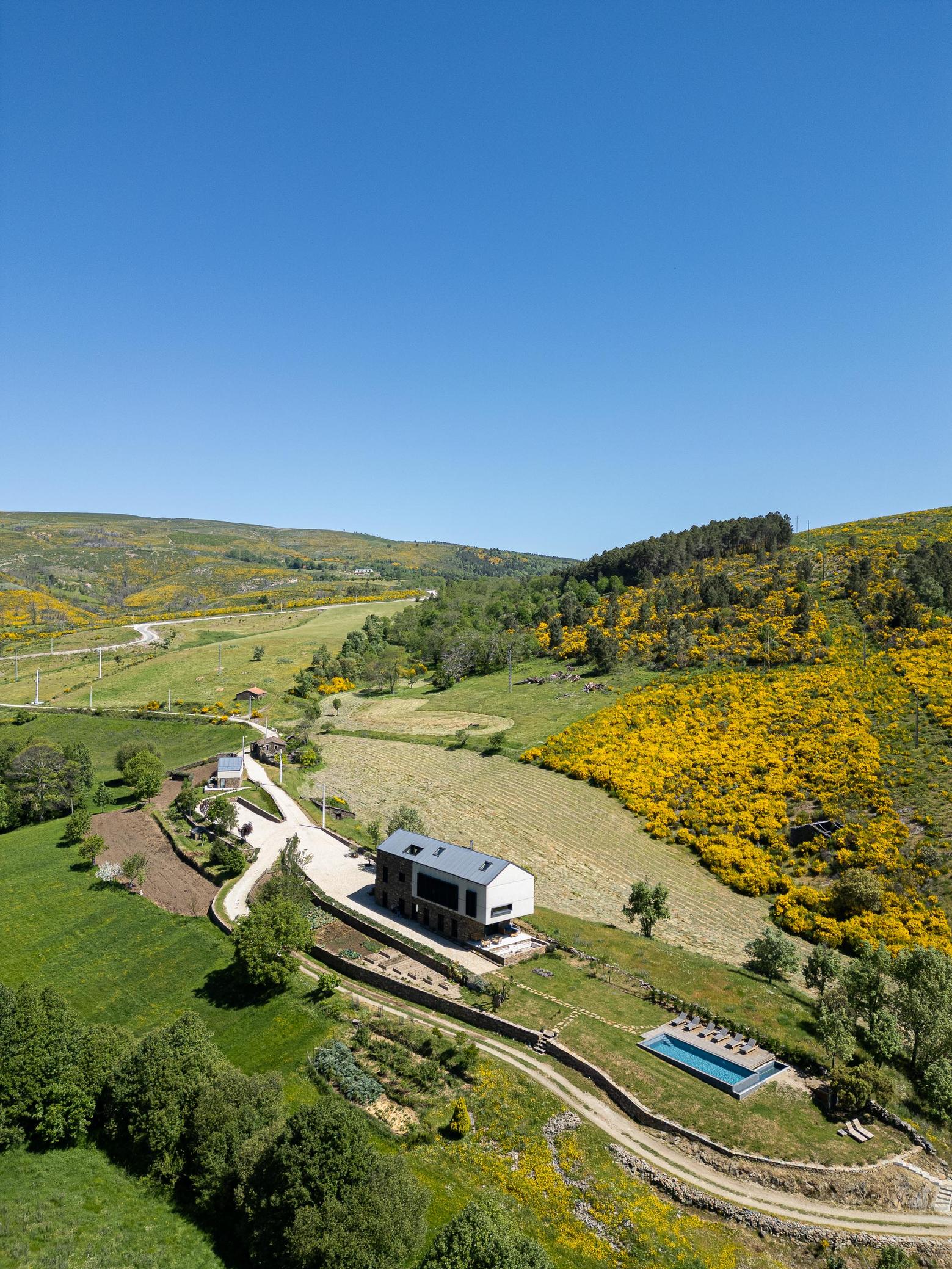 Exterior: Vista aérea da propriedade com casa principal, piscina e anexo, em paisagem montanhosa. — TerraSense Mountain Charm Retreat arquitetura DRK Atelier em Guarda