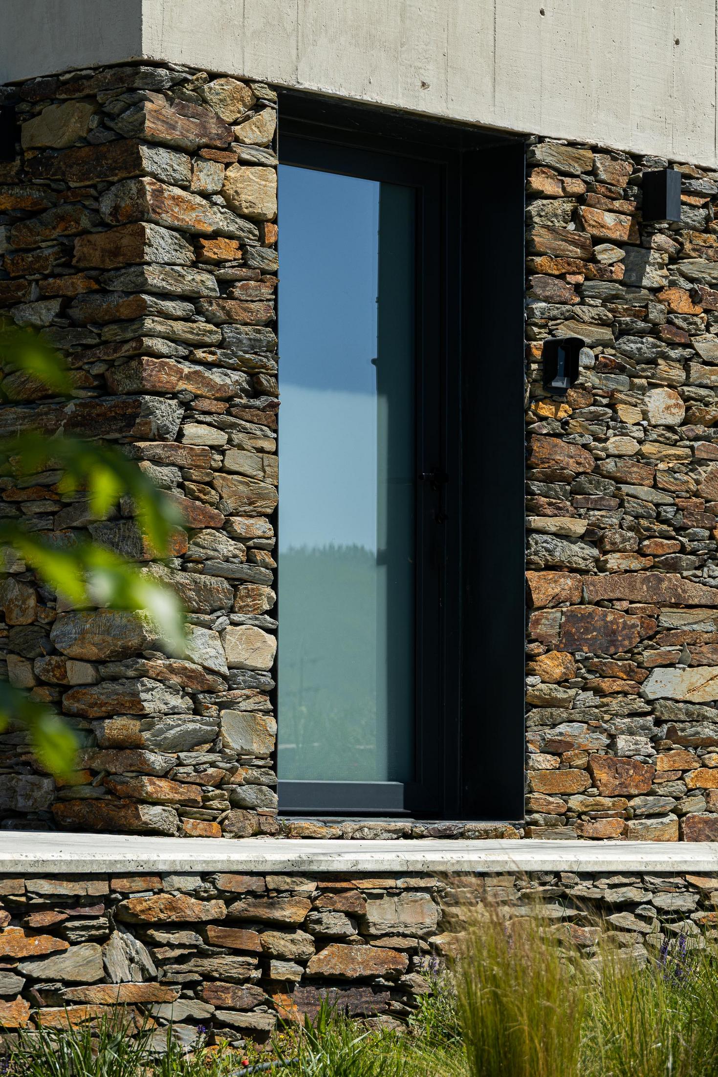Exterior: Detalhe de porta envidraçada com moldura preta, em fachada de pedra. — TerraSense Mountain Charm Retreat arquitetura DRK Atelier em Guarda