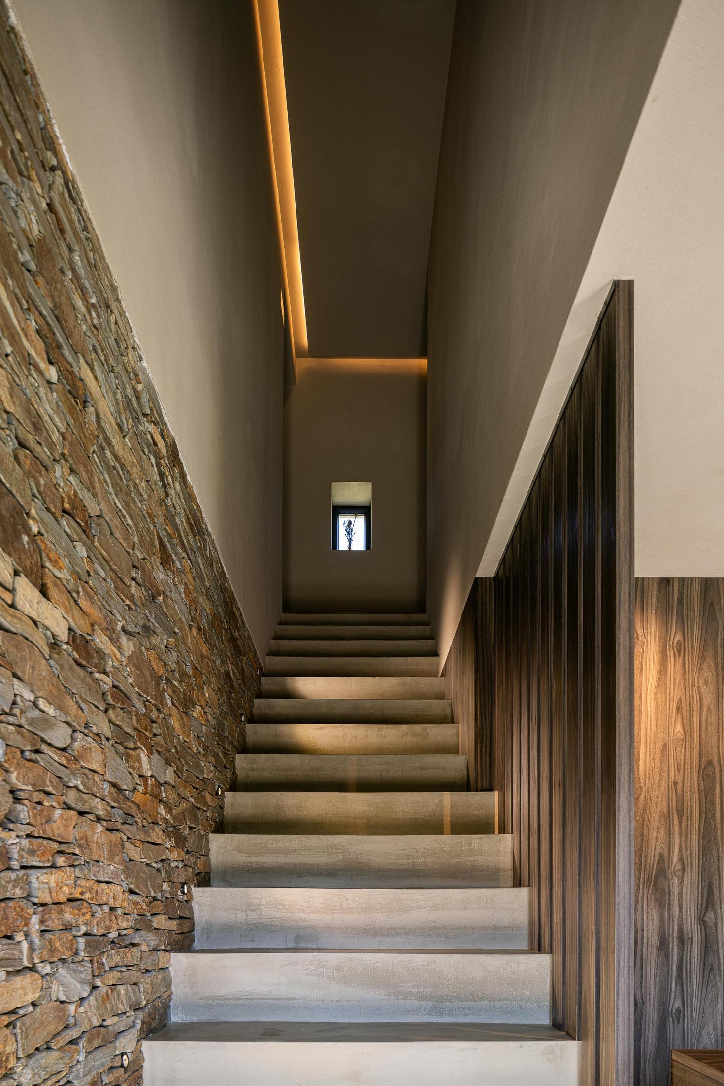 Escadas: Escadas em betão com parede em pedra e corrimão em madeira escura. — TerraSense Mountain Charm Retreat arquitetura DRK Atelier em Guarda