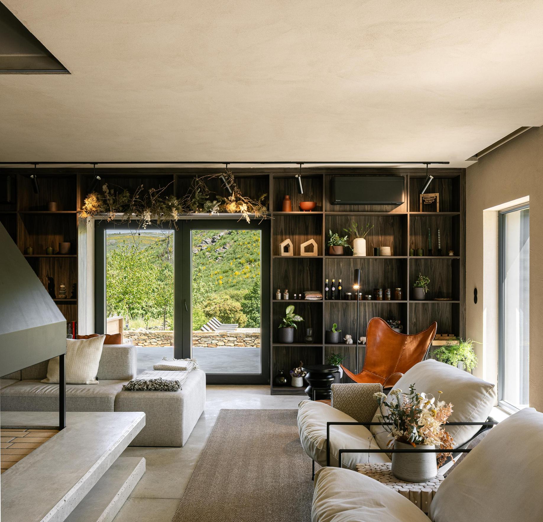 Sala de estar: Sofás claros, lareira moderna, estante em madeira escura e vista para o exterior. — TerraSense Mountain Charm Retreat arquitetura DRK Atelier em Guarda