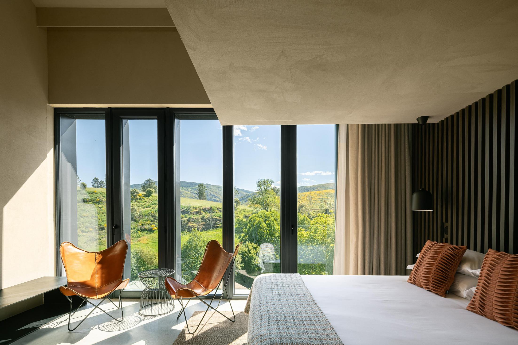 Quarto: Cama de casal com vista panorâmica e cadeiras de pele. — TerraSense Mountain Charm Retreat arquitetura DRK Atelier em Guarda