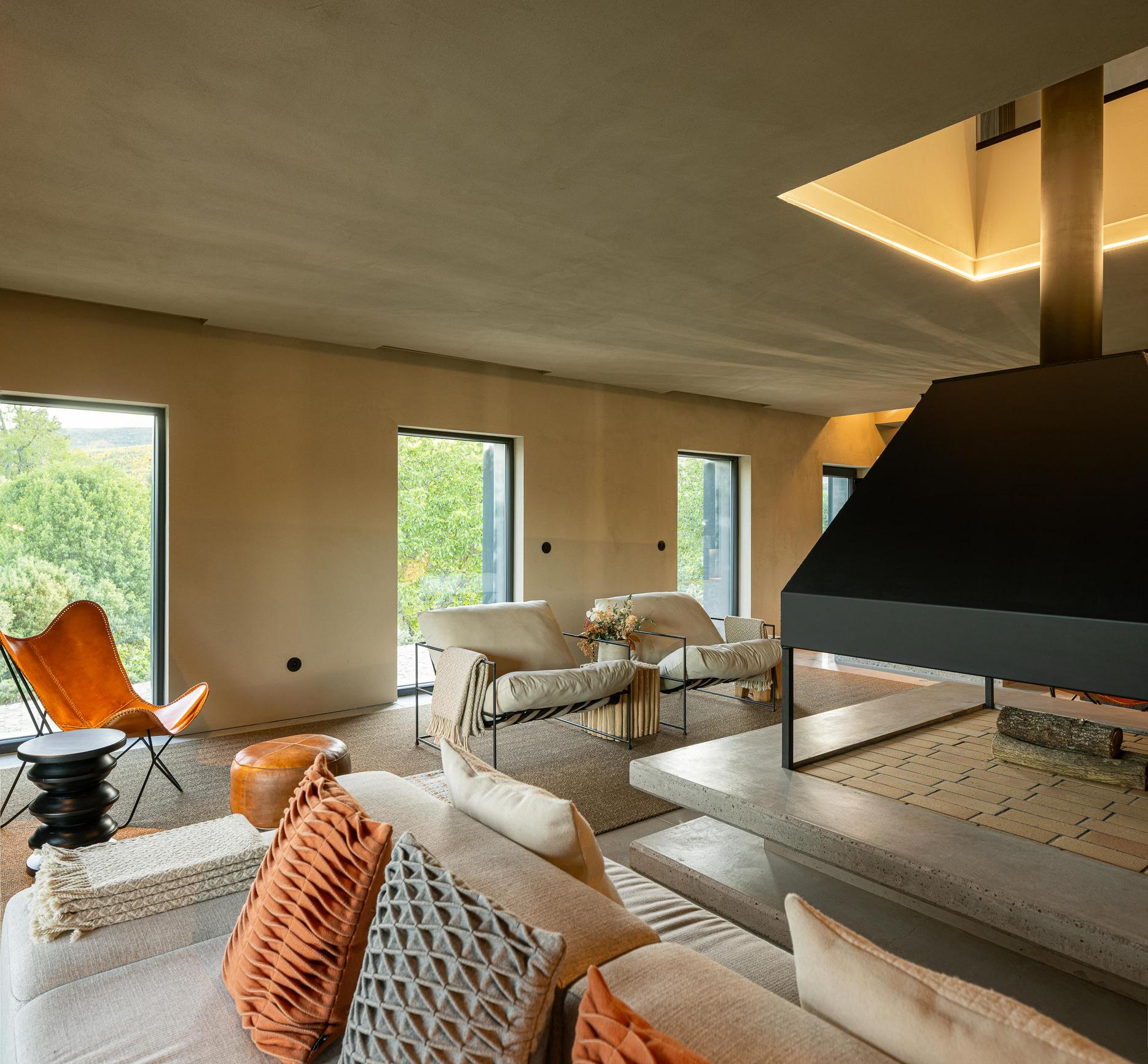 Sala de estar: Sofá claro, estante em madeira escura e cadeiras de pele. — TerraSense Mountain Charm Retreat arquitetura DRK Atelier em Guarda