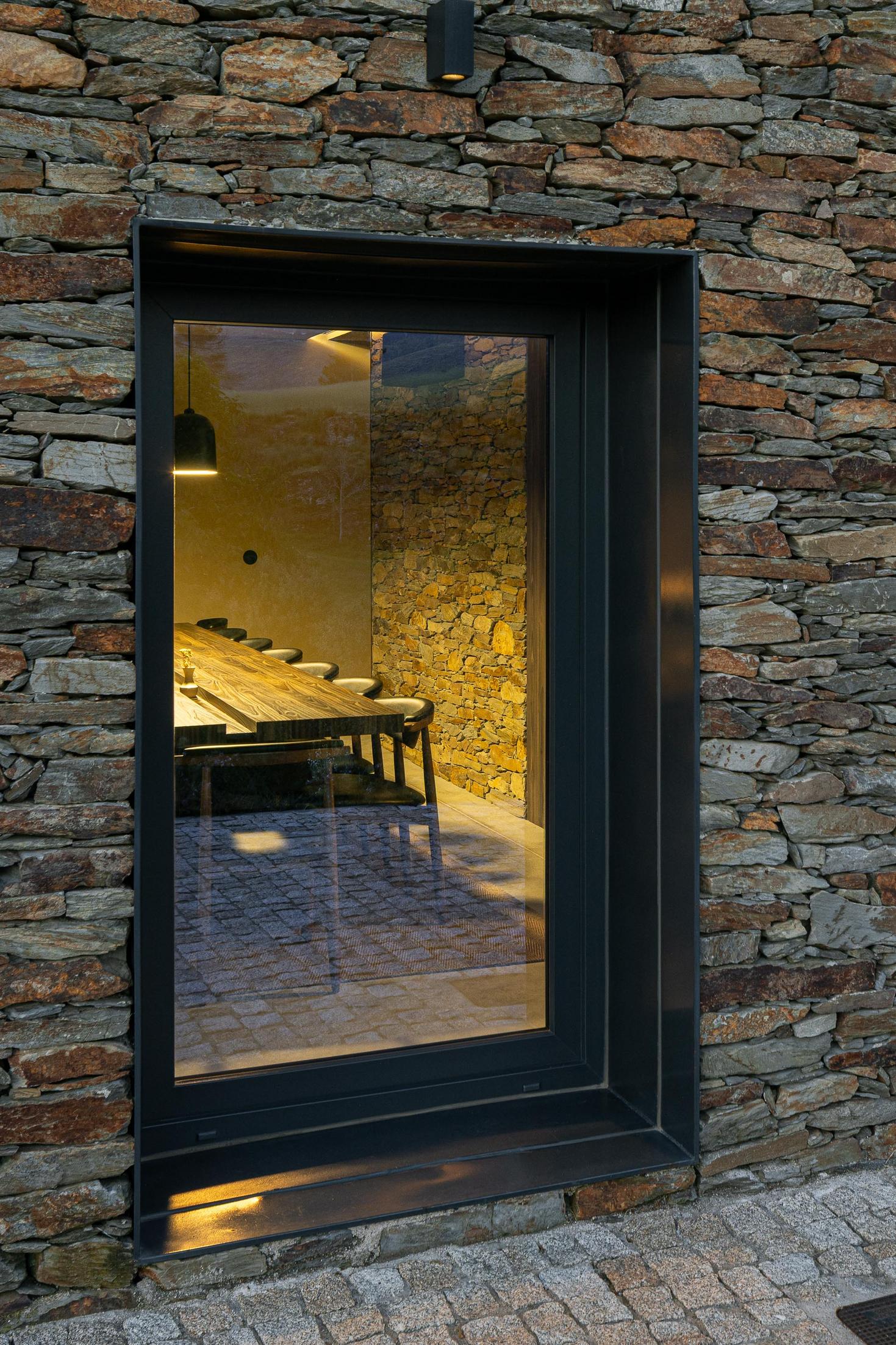 Exterior: Fachada lateral da casa com revestimento em pedra e betão, ao entardecer. — TerraSense Mountain Charm Retreat arquitetura DRK Atelier em Guarda