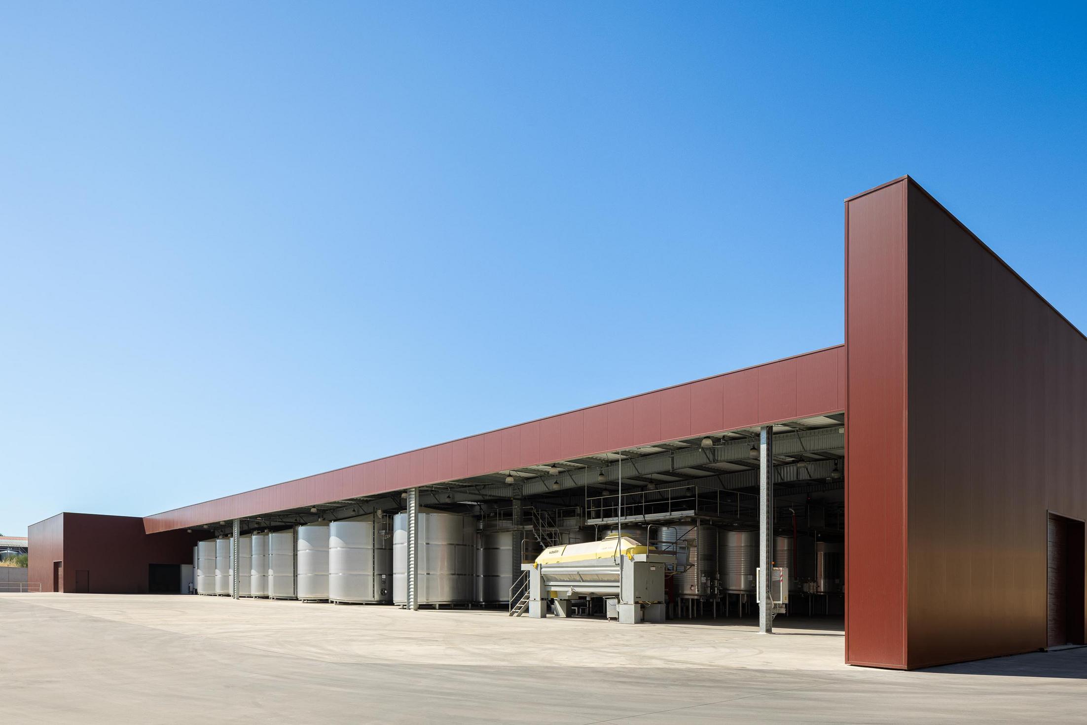Exterior: Edifício industrial com revestimento cor de vinho e zona de tanques de inox. — Adega Vinhos Borges arquitetura Em Paralelo em Vila Real