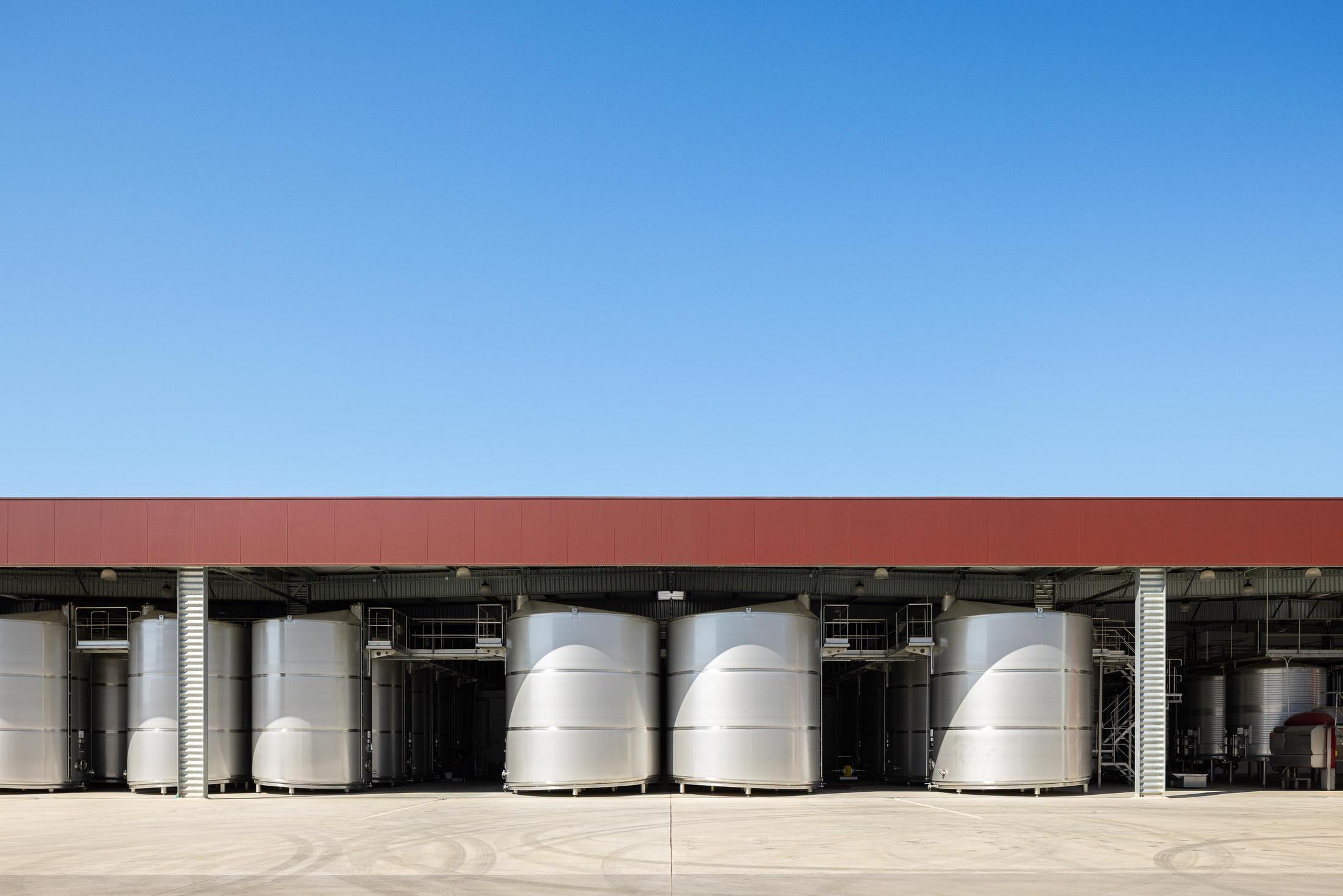Exterior: Zona de tanques de inox para produção de vinho, sob estrutura metálica coberta. — Adega Vinhos Borges arquitetura Em Paralelo em Vila Real