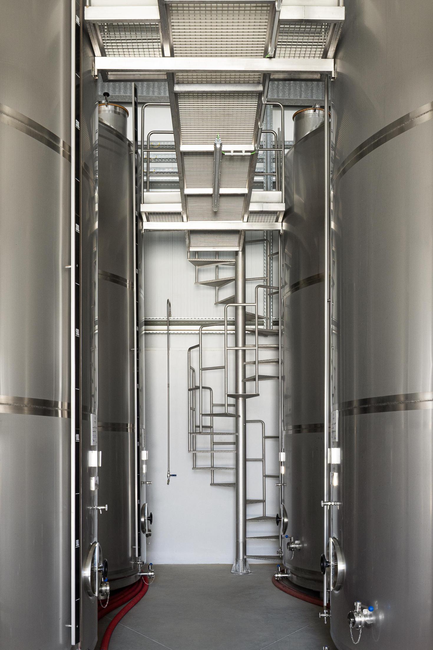 Zona de produção: Interior com tanques de inox, passadiços e escada em caracol. — Adega Vinhos Borges arquitetura Em Paralelo em Vila Real
