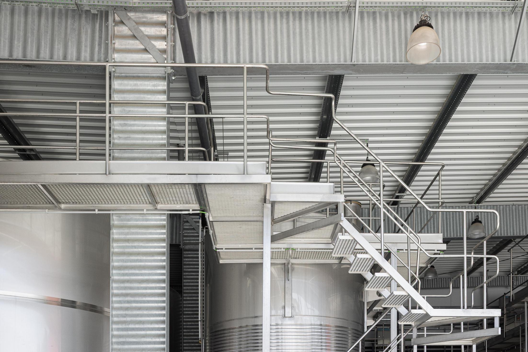 Zona de produção: Detalhe da estrutura metálica, escadas e tanques de inox. — Adega Vinhos Borges arquitetura Em Paralelo em Vila Real