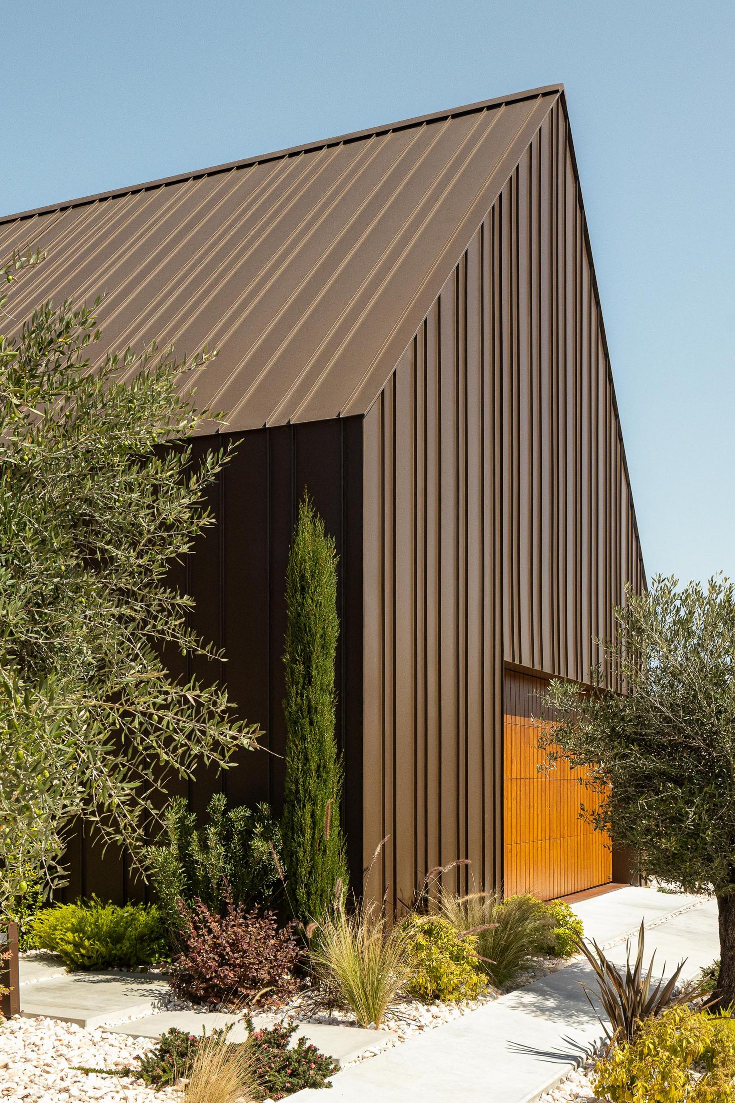 Exterior: Detalhe da fachada revestida a metal castanho, com vegetação rasteira. — House SM arquitetura Mário Alves Arquitecto em Ílhavo
