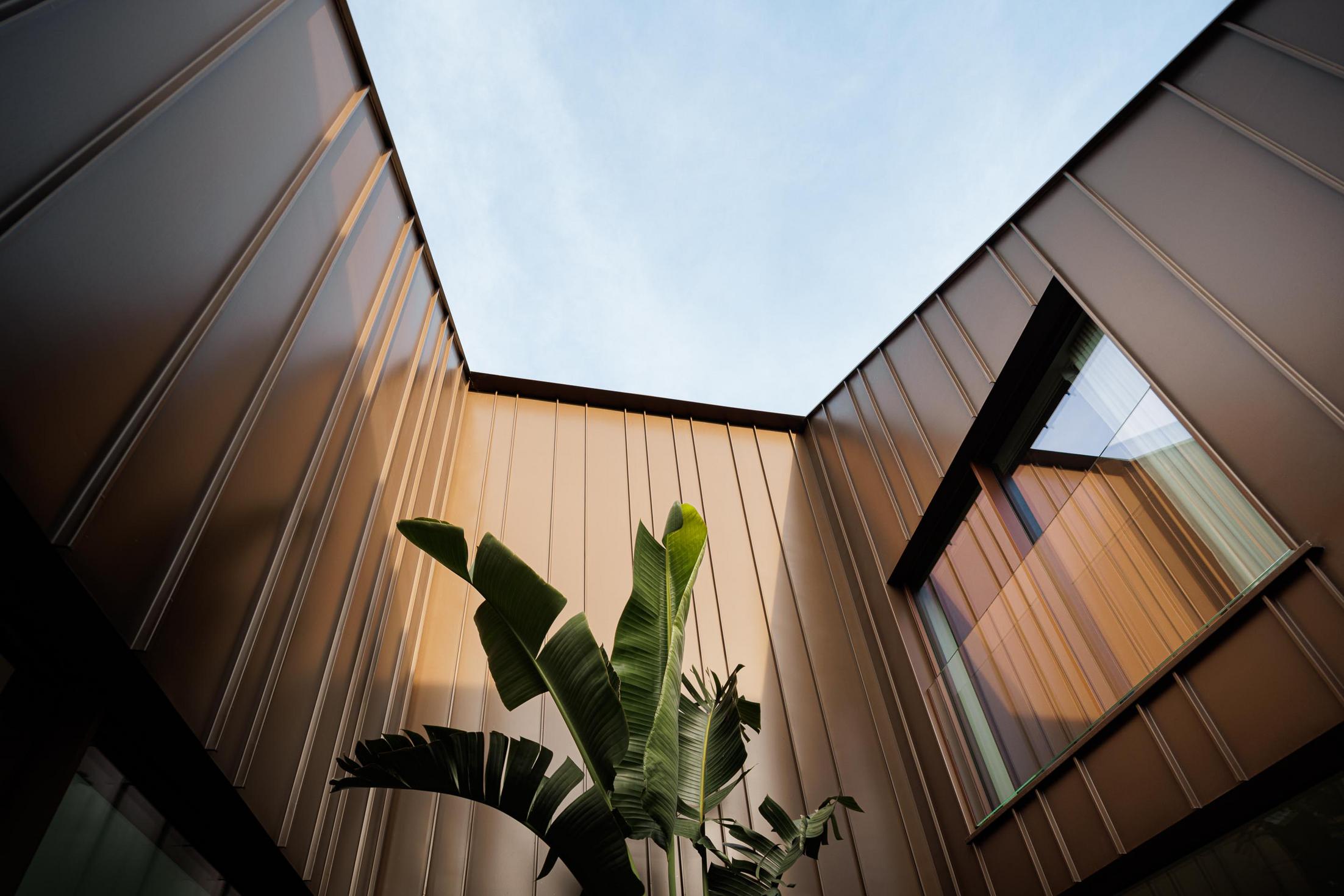 Pátio interior: Vista ascendente do pátio interior com revestimento metálico castanho. — House SM arquitetura Mário Alves Arquitecto em Ílhavo