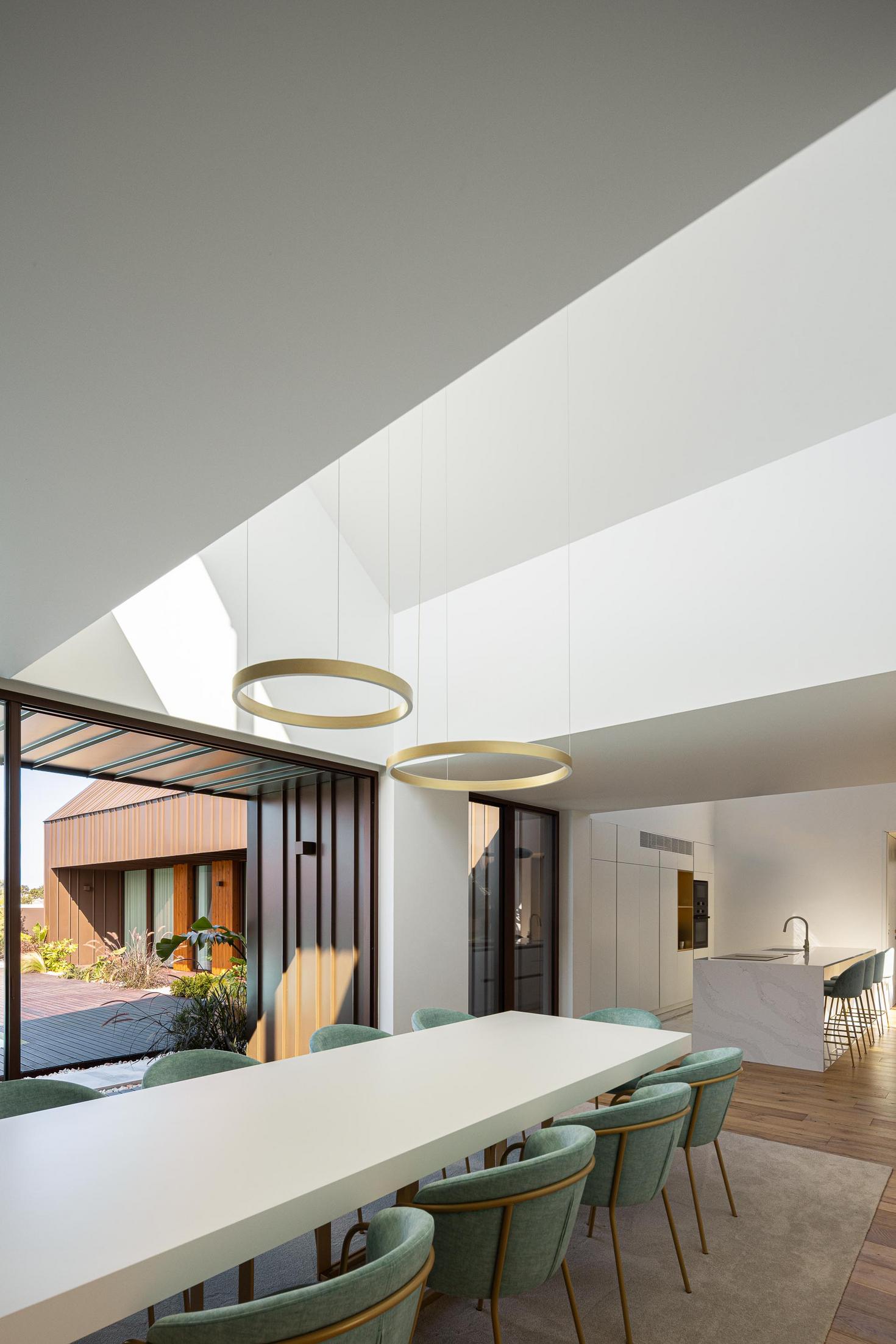 Sala de jantar: Mesa branca com cadeiras turquesa, candeeiros circulares e alcatifa cinzenta. — House SM arquitetura Mário Alves Arquitecto em Ílhavo