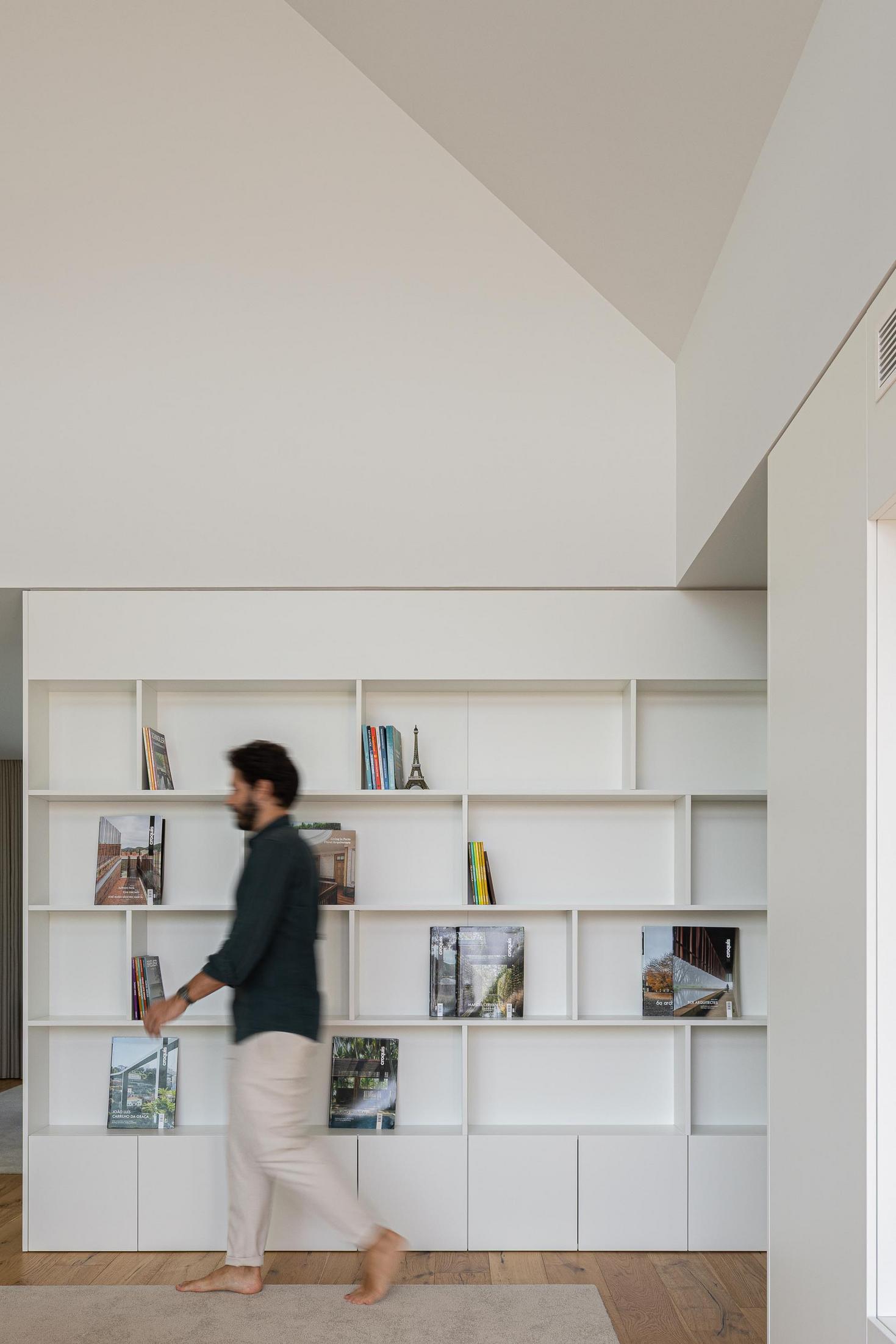 Escritório/Biblioteca: Estante branca com livros e pavimento em madeira. — House SM arquitetura Mário Alves Arquitecto em Ílhavo