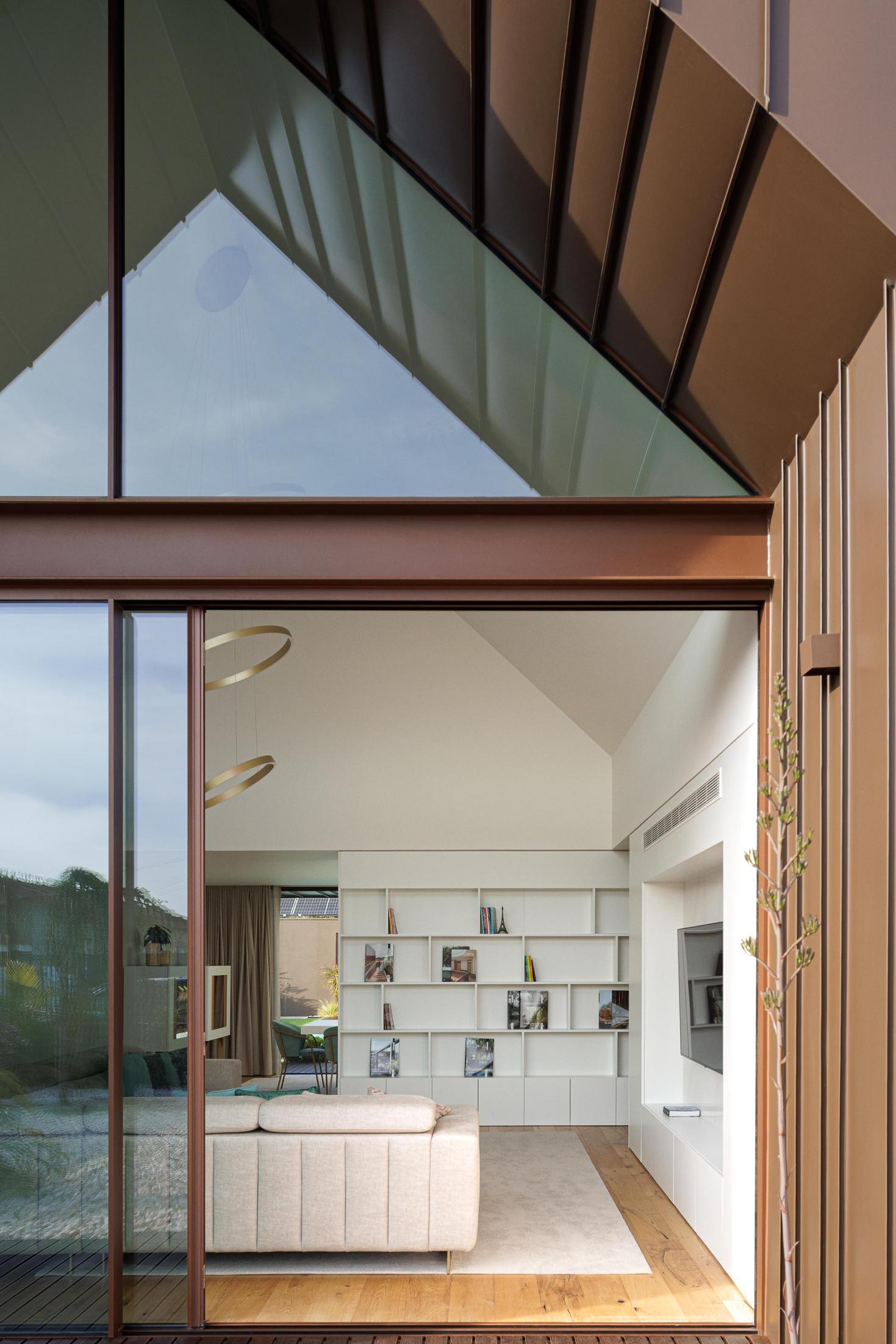 Sala de estar: Vista da sala de estar para o exterior, com sofá, estante e candeeiros circulares. — House SM arquitetura Mário Alves Arquitecto em Ílhavo