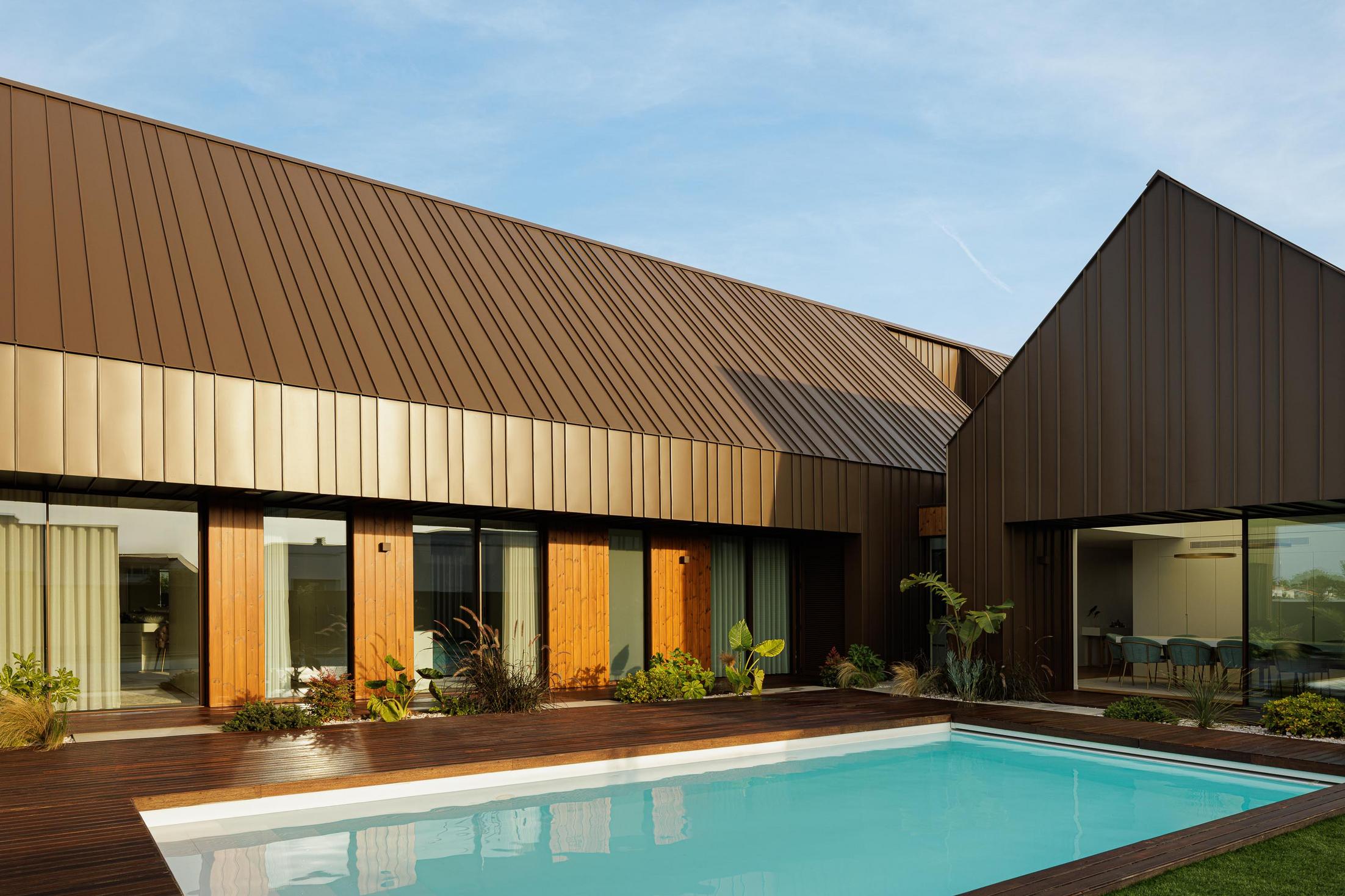 Exterior: Piscina com deck em madeira e vista para a fachada posterior da casa. — House SM arquitetura Mário Alves Arquitecto em Ílhavo