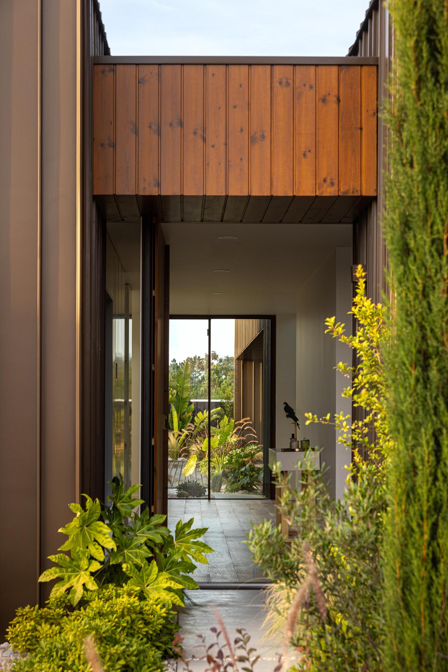 Entrada: Perspectiva da entrada com porta de madeira e vista para o pátio interior. — House SM arquitetura Mário Alves Arquitecto em Ílhavo