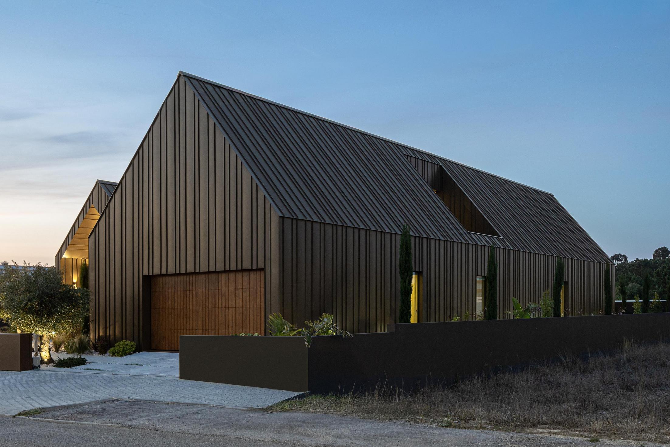 Exterior: Vista geral da casa ao entardecer com revestimento metálico castanho. — House SM arquitetura Mário Alves Arquitecto em Ílhavo