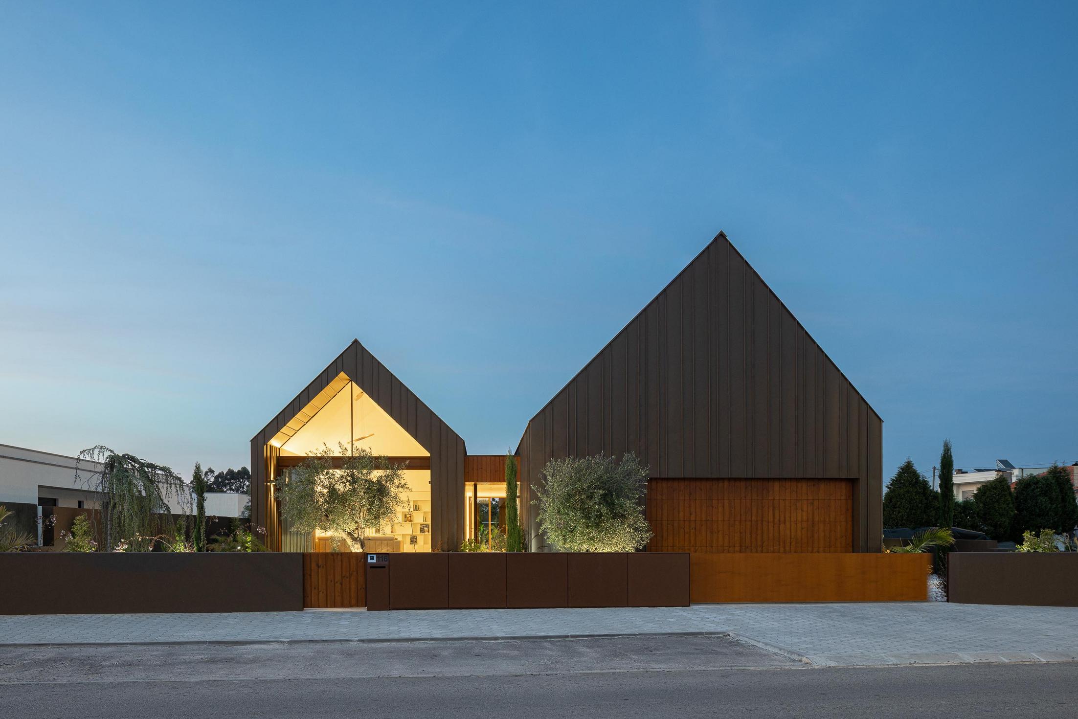 Exterior: Vista frontal da casa ao entardecer com revestimento metálico castanho. — House SM arquitetura Mário Alves Arquitecto em Ílhavo