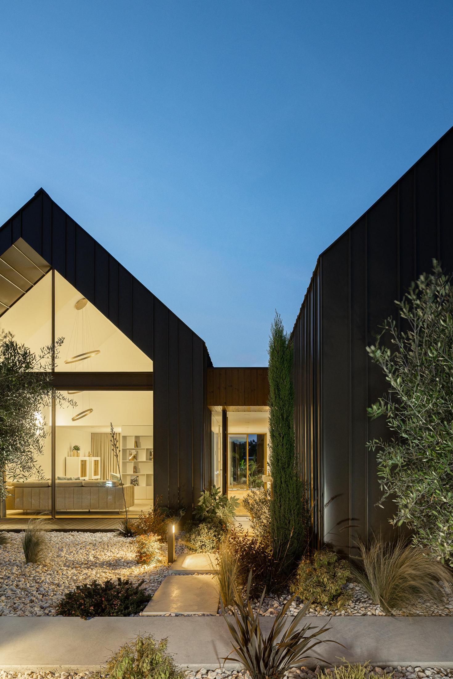 Entrada: Vista da entrada iluminada com caminho de pedra branca e vegetação. — House SM arquitetura Mário Alves Arquitecto em Ílhavo