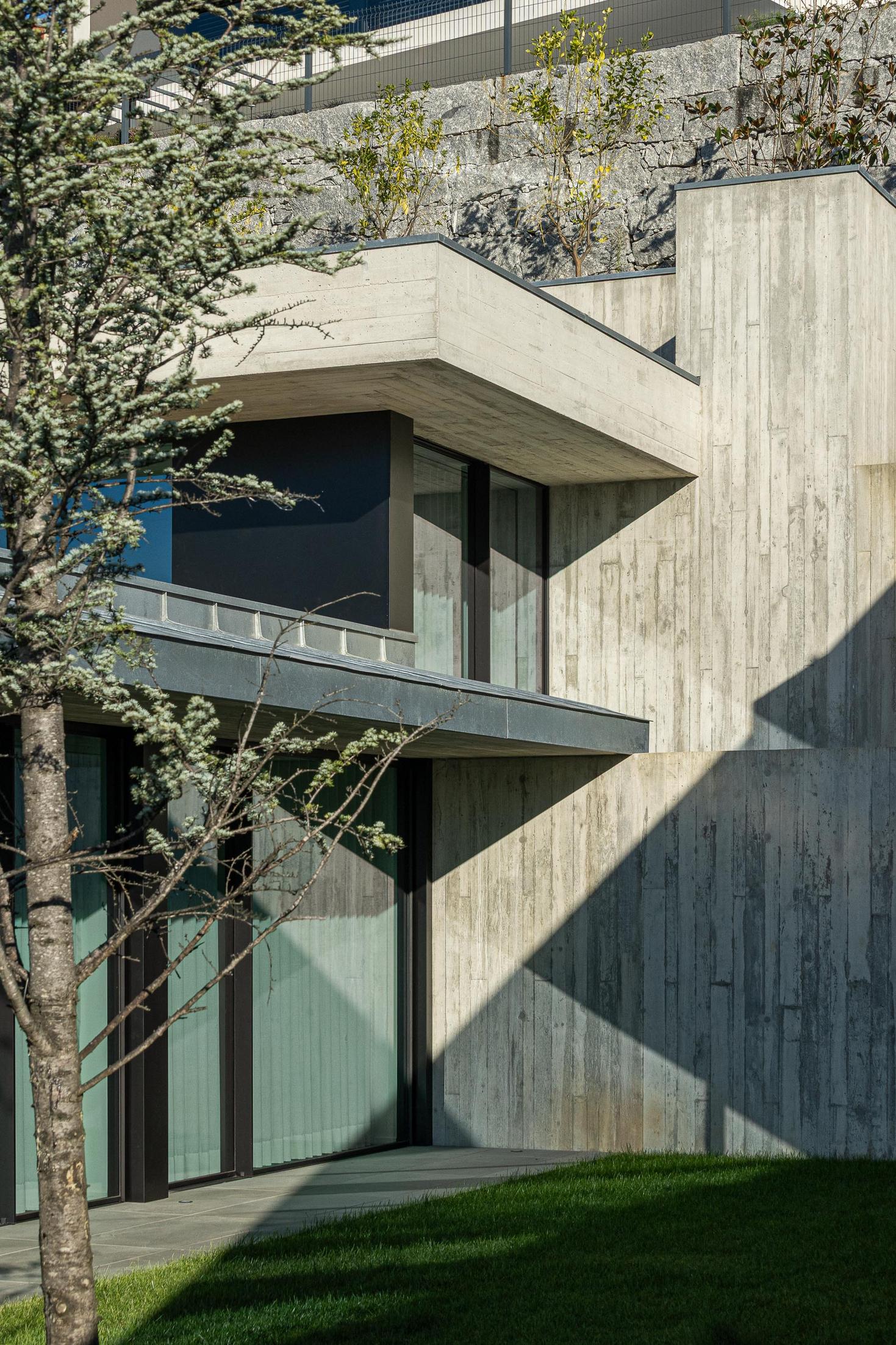 Exterior: Pátio com piscina, relvado, e fachada envidraçada da sala, com vista panorâmica. — CASA A arquitetura L2C Arquitetura em Braga