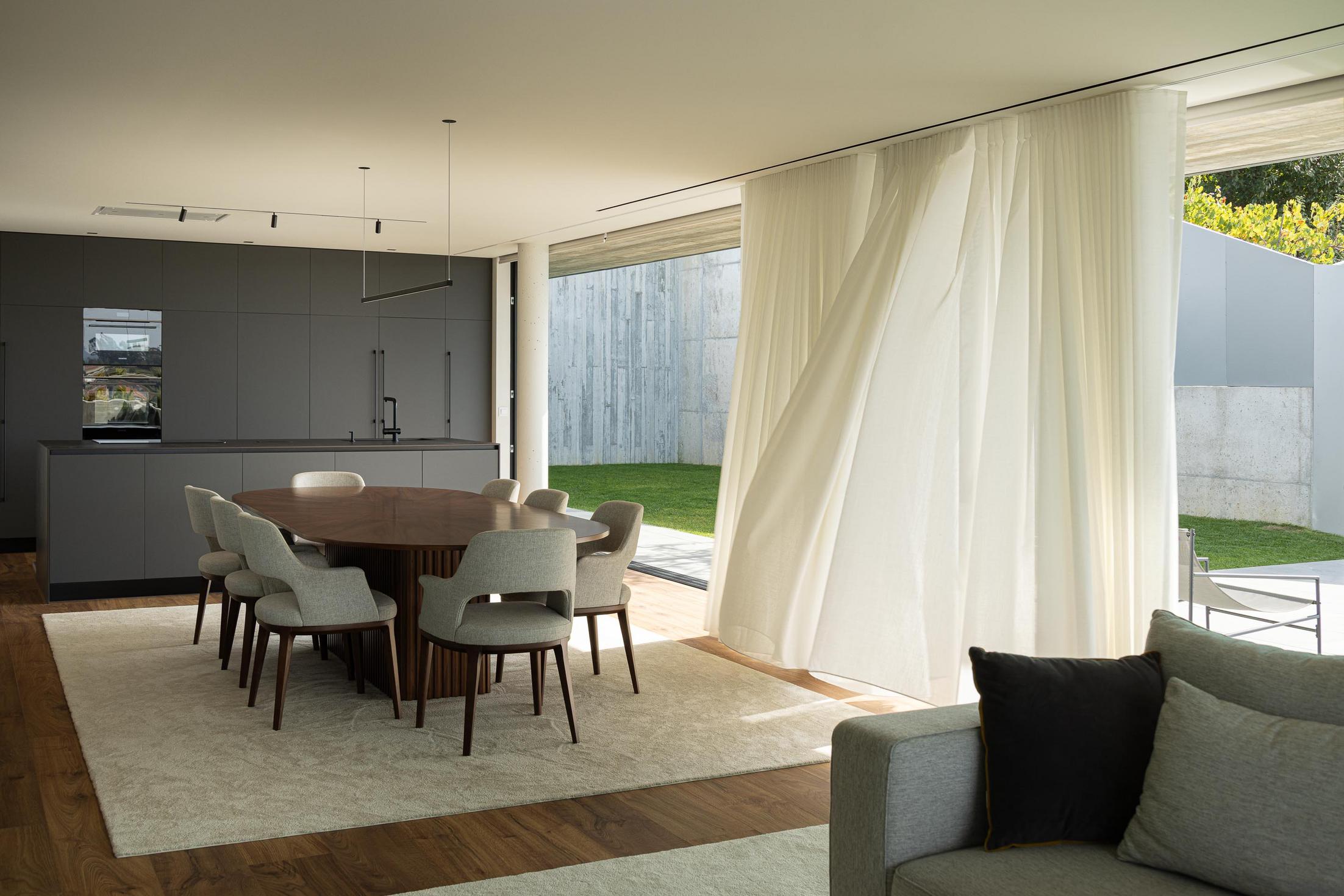 Cozinha: Ilha central minimalista em tons escuros, com armários embutidos e iluminação direcionada. — CASA A arquitetura L2C Arquitetura em Braga