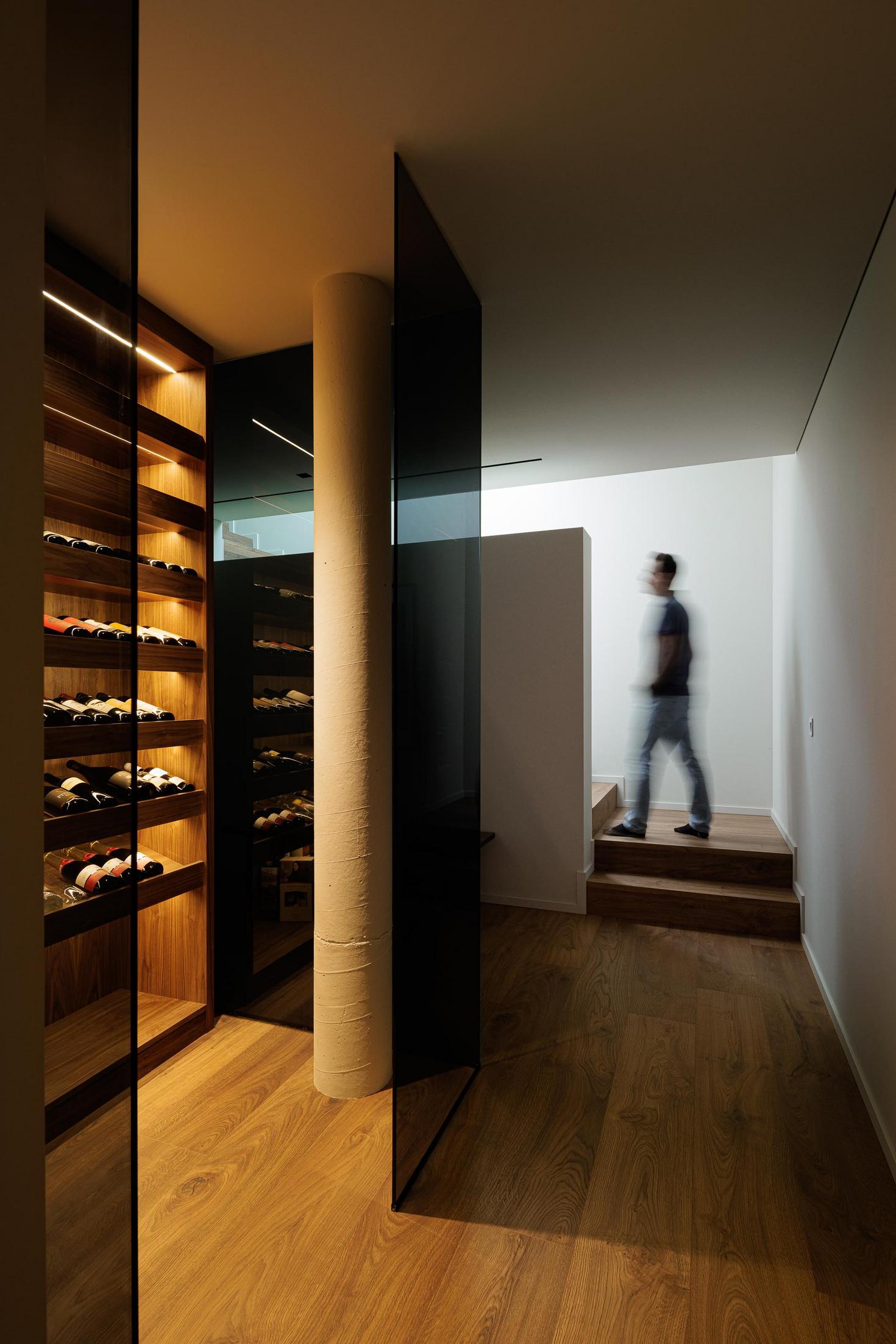 Sala de estar/Jantar: Estante em madeira com objetos decorativos e mesa de jantar redonda. — CASA A arquitetura L2C Arquitetura em Braga