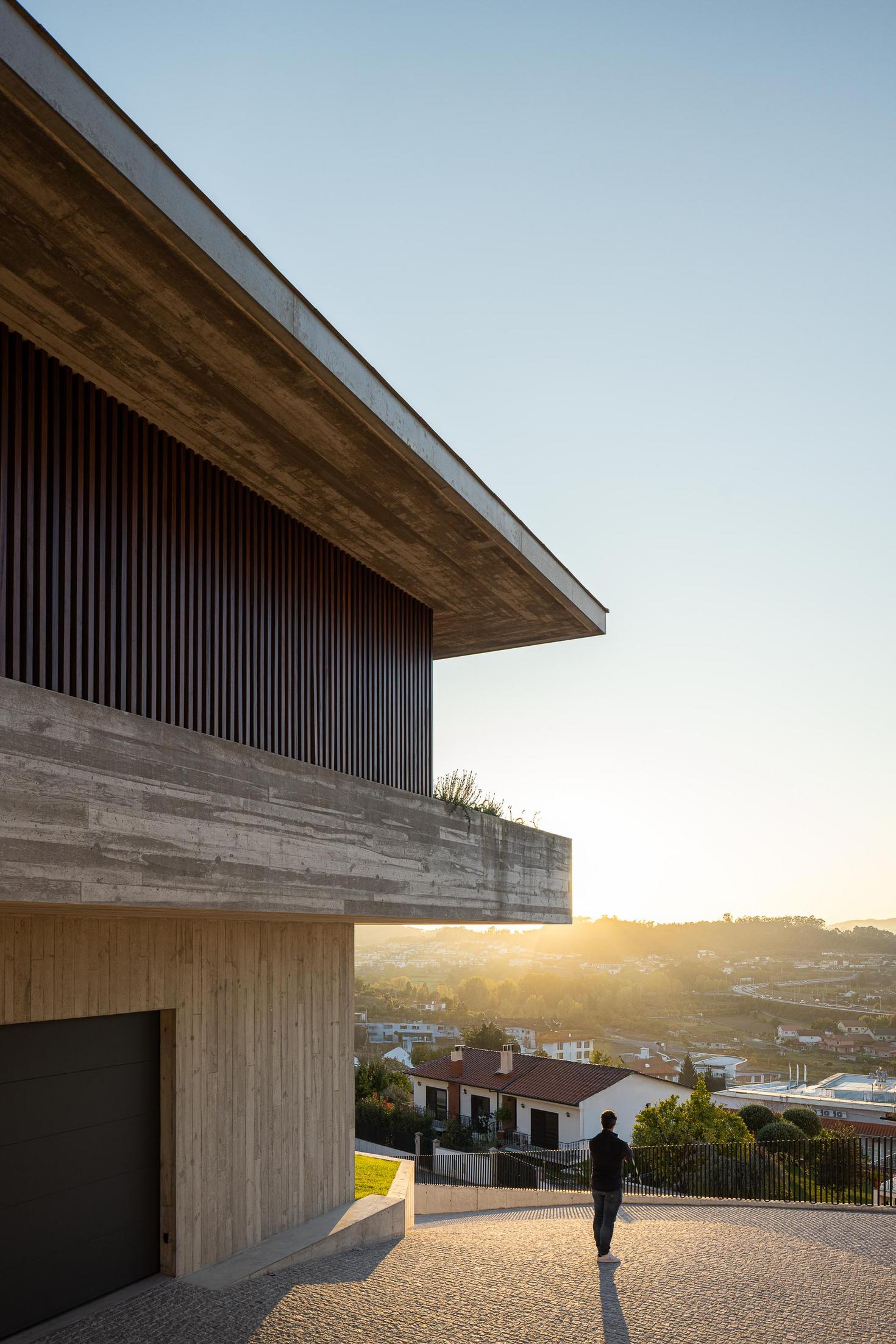 Exterior: Alpendre com cadeiras e vista para a paisagem, com detalhes em betão aparente. — CASA A arquitetura L2C Arquitetura em Braga