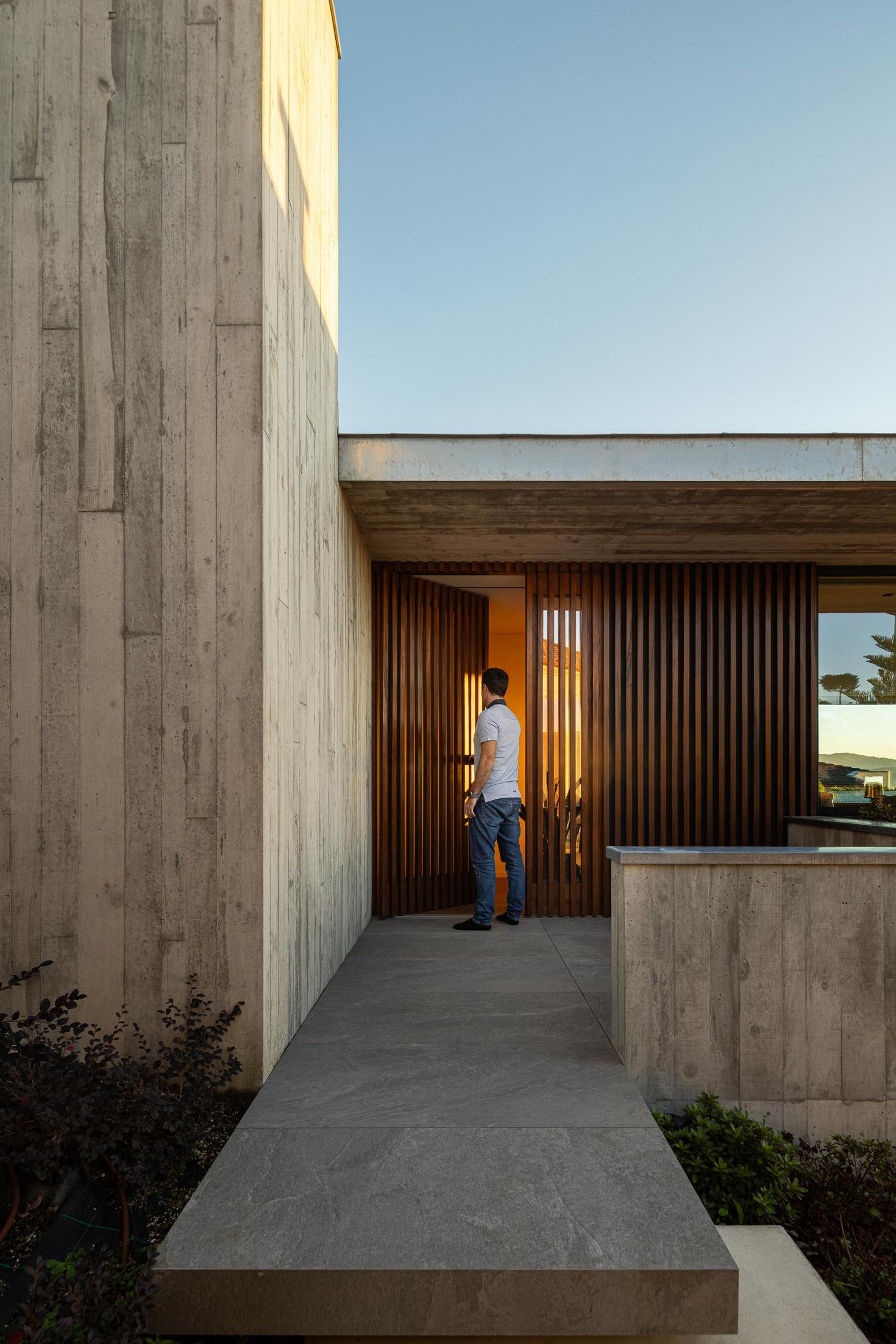 Exterior: Fachada com ripas de madeira e betão aparente, com vista para a paisagem ao pôr do sol. — CASA A arquitetura L2C Arquitetura em Braga