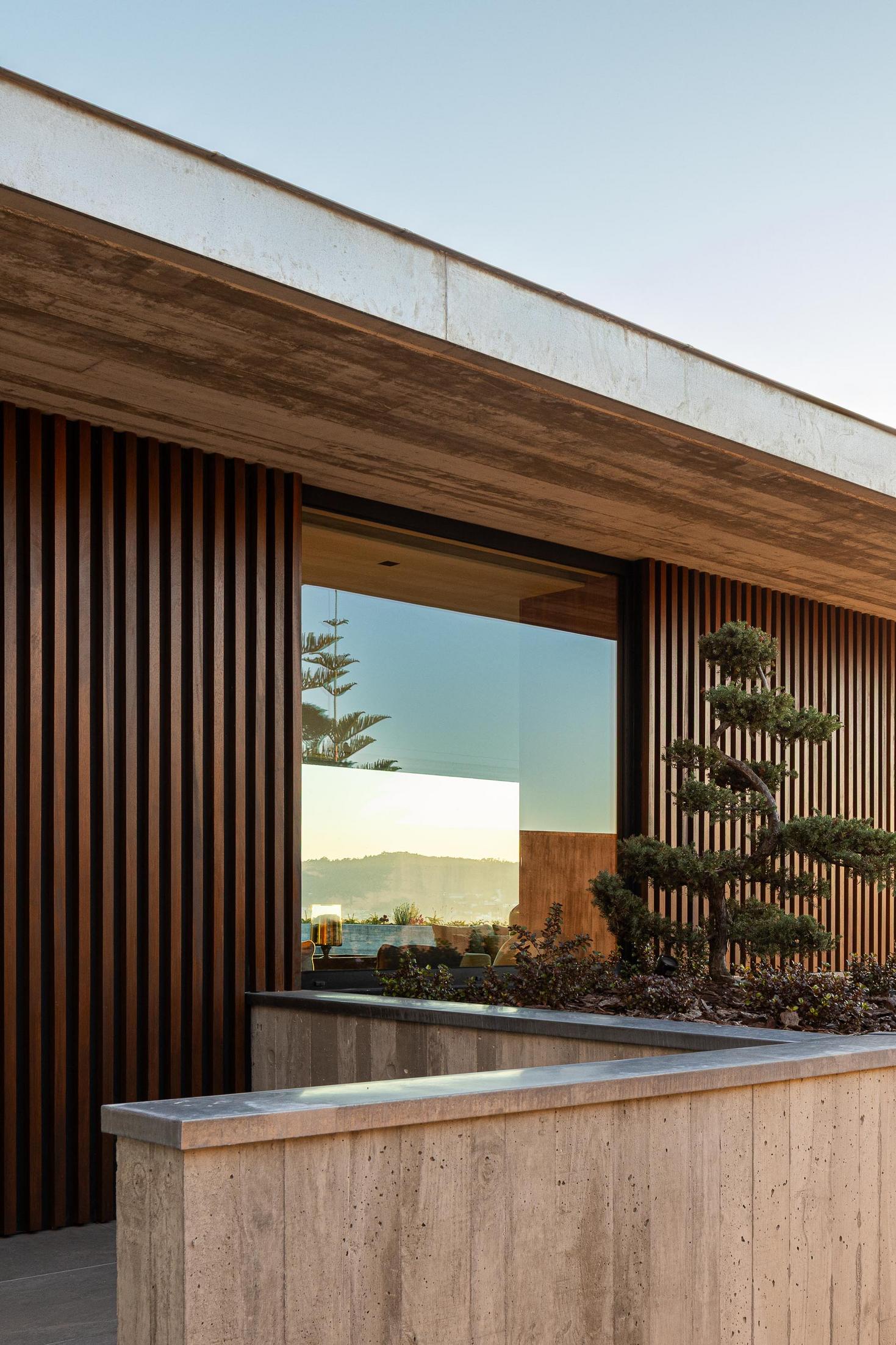 Exterior: Floreira em betão aparente com planta e fachada com ripas de madeira. — CASA A arquitetura L2C Arquitetura em Braga
