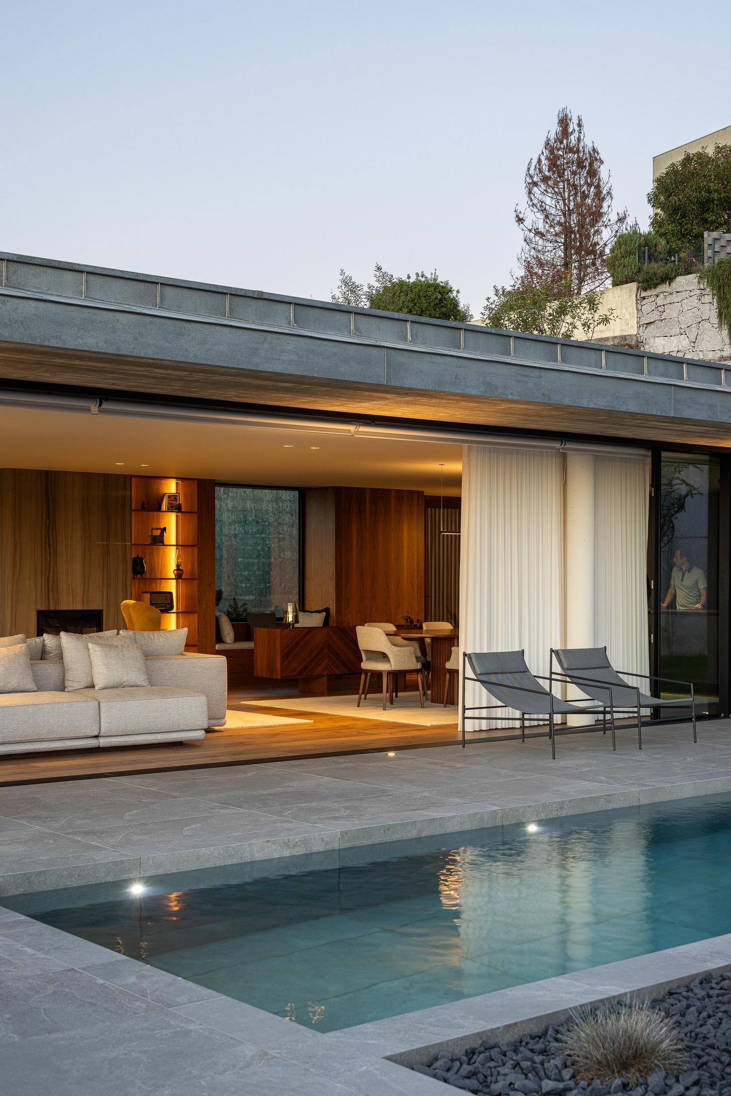 Exterior: Alpendre com sala de estar e jantar, com vista para a paisagem ao entardecer. — CASA A arquitetura L2C Arquitetura em Braga