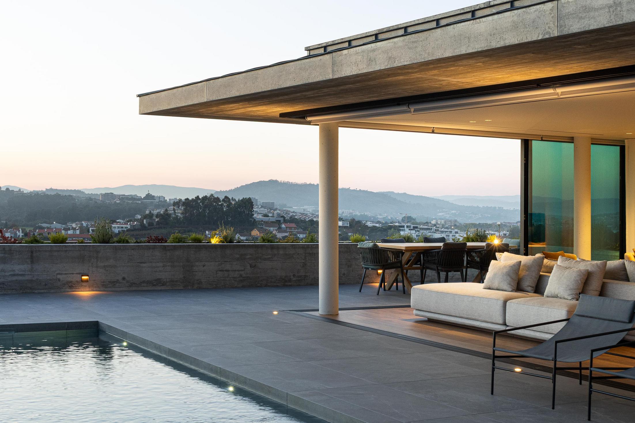 Exterior: Vista panorâmica da cidade ao entardecer, com a casa e a piscina em primeiro plano. — CASA A arquitetura L2C Arquitetura em Braga