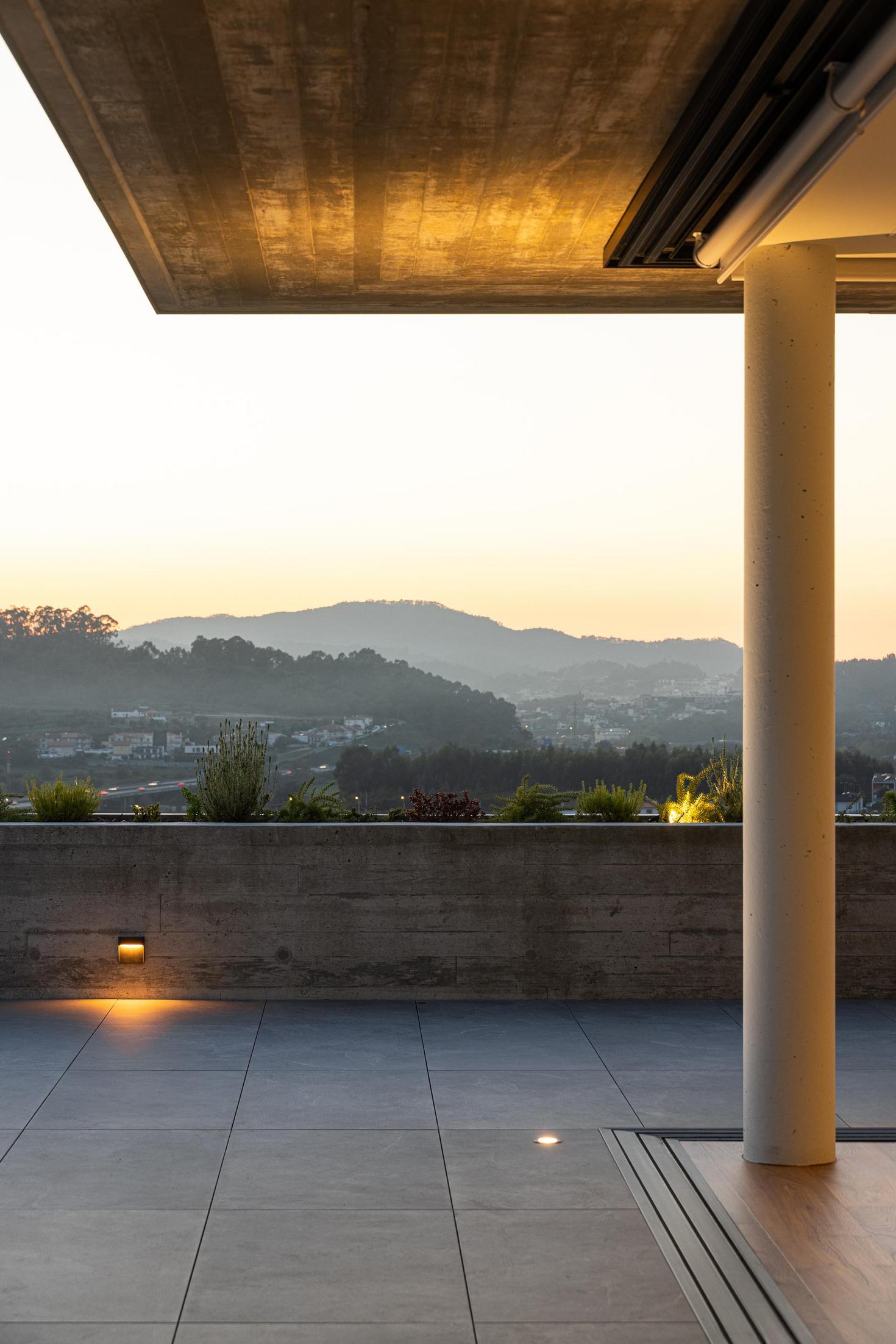 Exterior: Vista geral da casa ao entardecer, com piscina e iluminação exterior. — CASA A arquitetura L2C Arquitetura em Braga