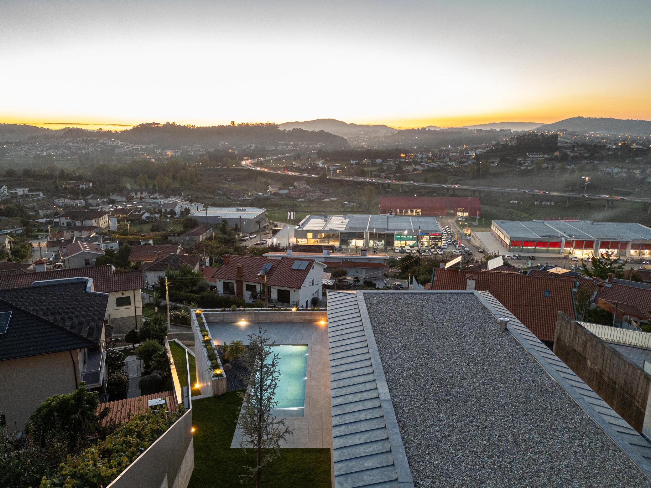 Exterior: Detalhe da fachada com ripas de madeira e floreira iluminada ao entardecer. — CASA A arquitetura L2C Arquitetura em Braga