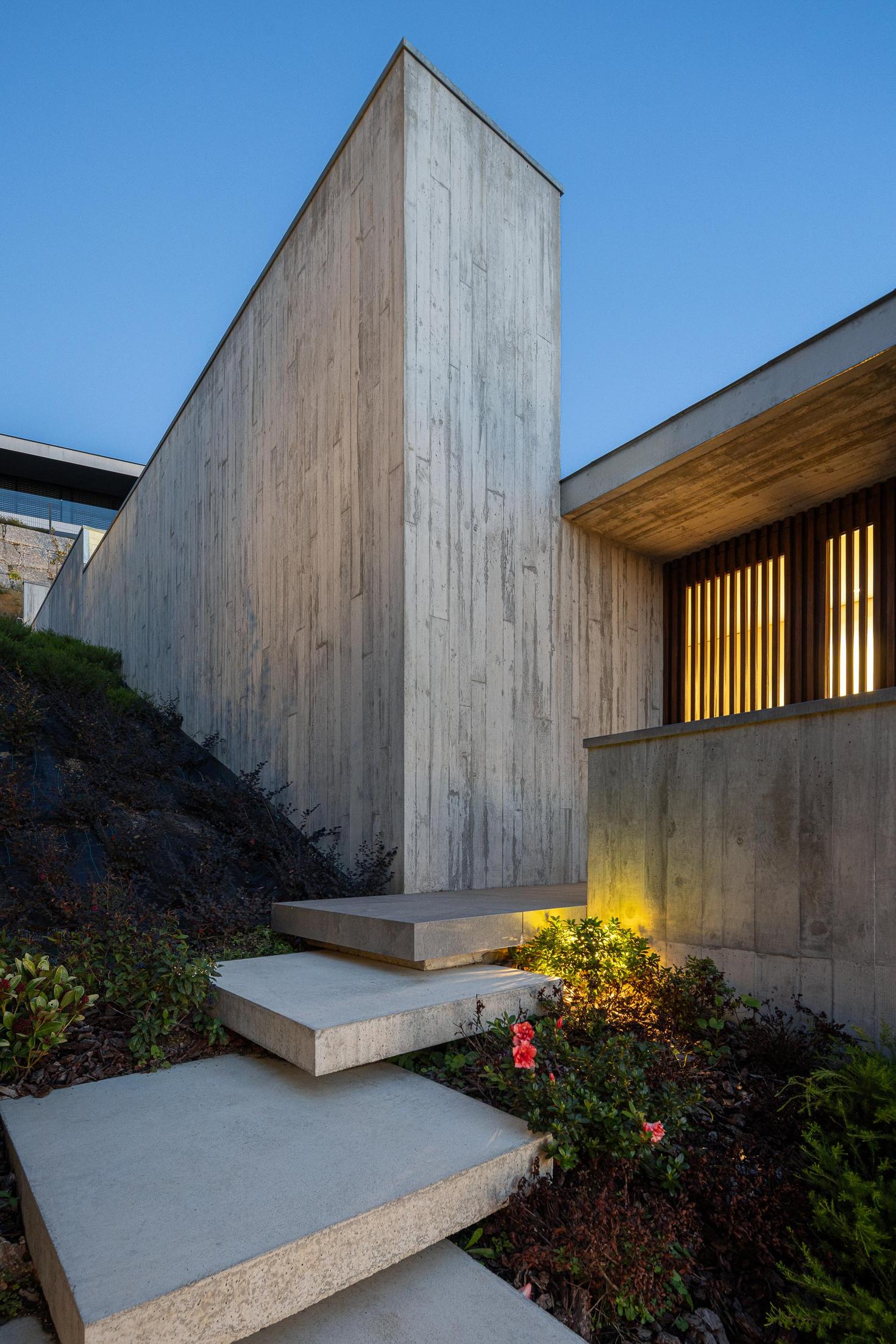 Exterior: Alpendre com piscina iluminada e vista para a paisagem ao anoitecer. — CASA A arquitetura L2C Arquitetura em Braga